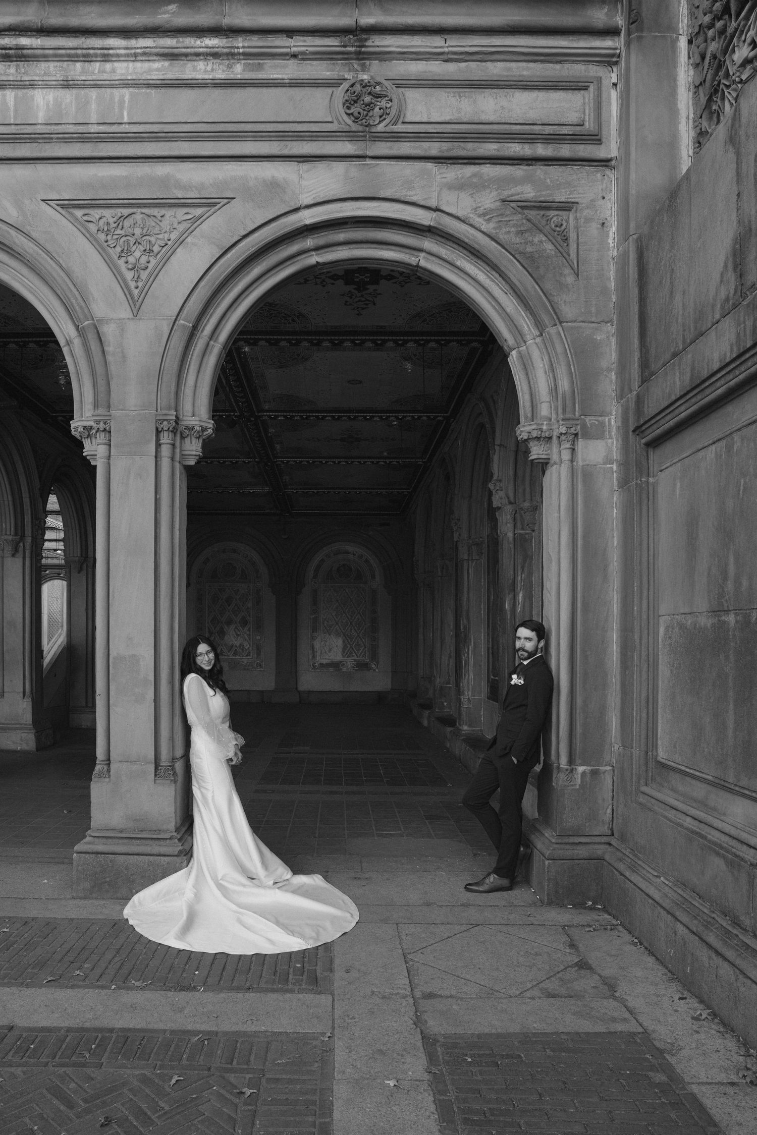 A series of black and white wedding photos showing a couple in an elegant stone archway corridor.