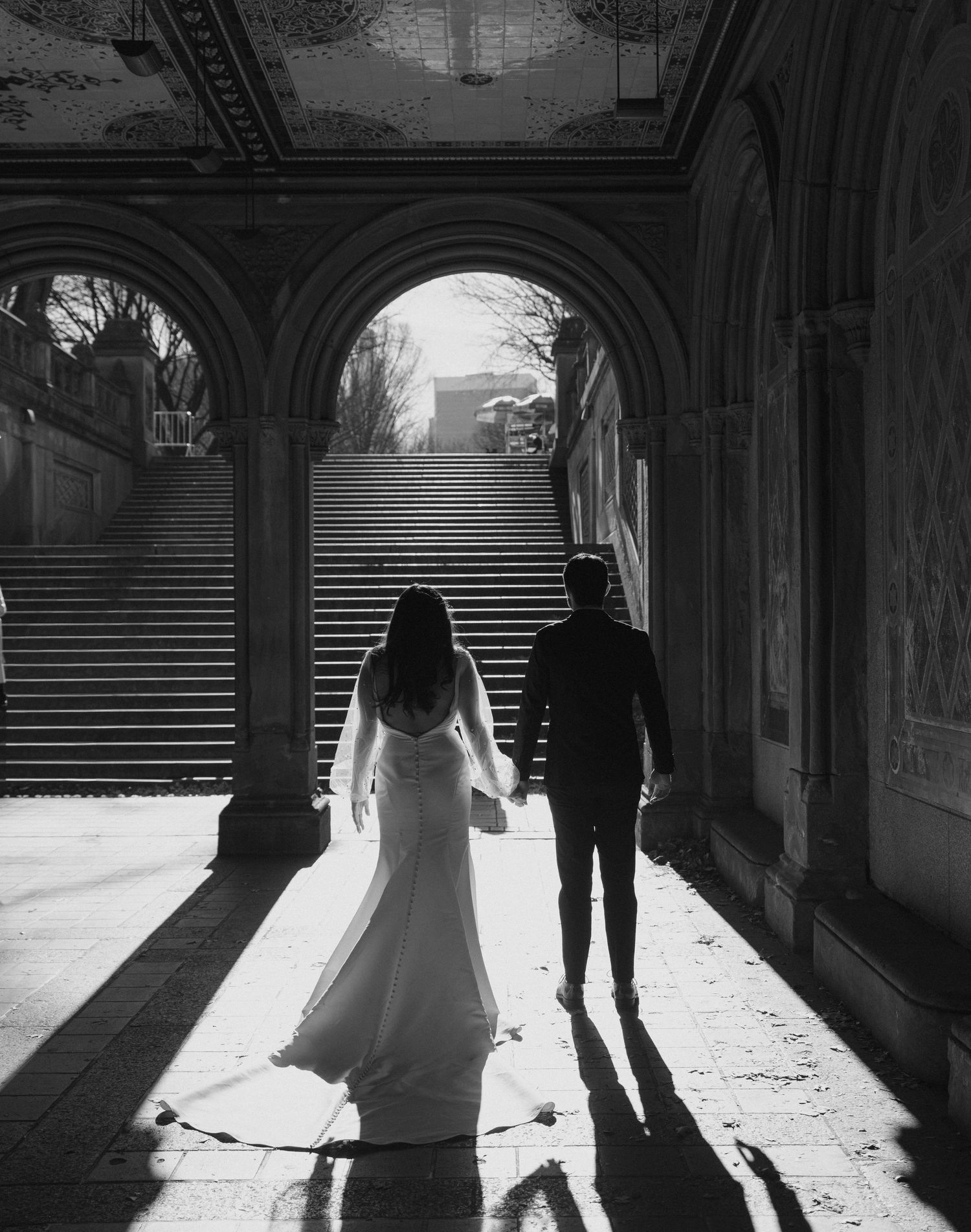 Silhouettes of a couple walking through Bethesda Terrace arcade in Central Park with dramatic backlighting.