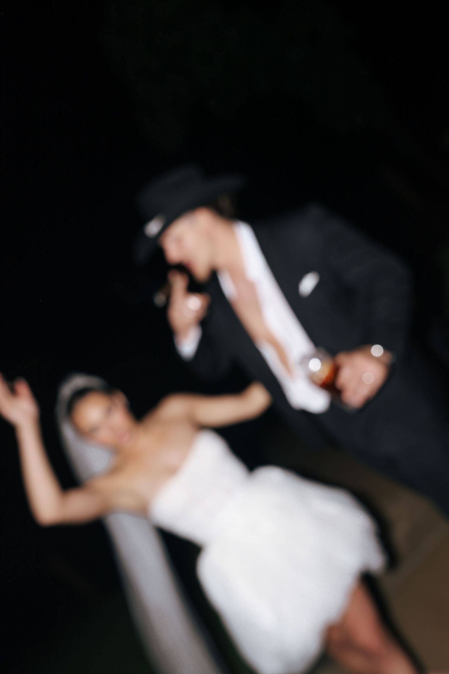 A couple in wedding attire posing together in the dark.
