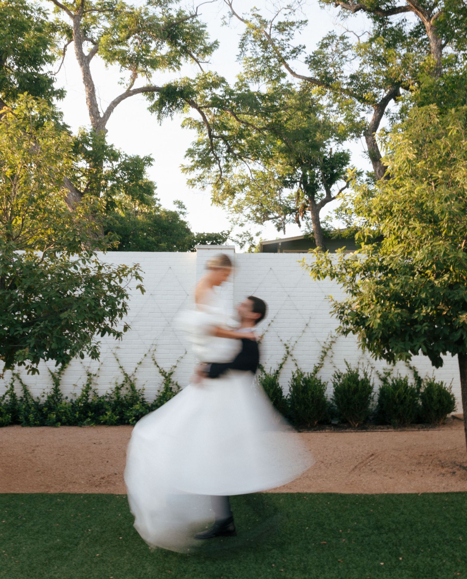 Motion blur sequence of someone twirling in white against a garden backdrop.