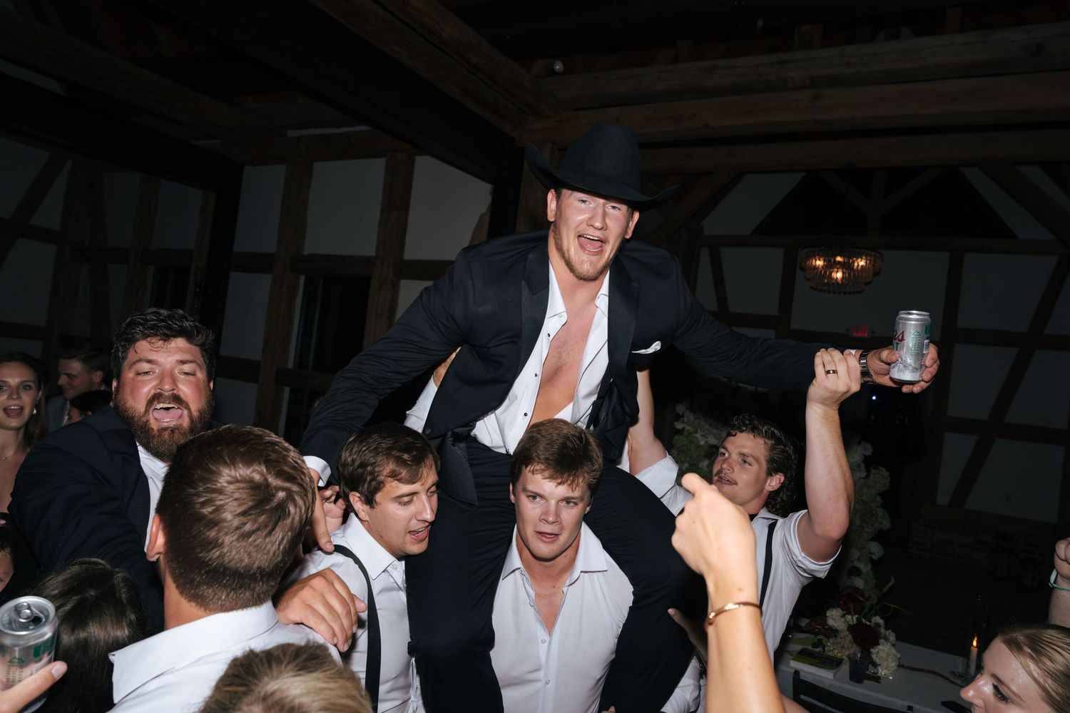 Energetic crowd dancing and celebrating at a dimly lit party venue.