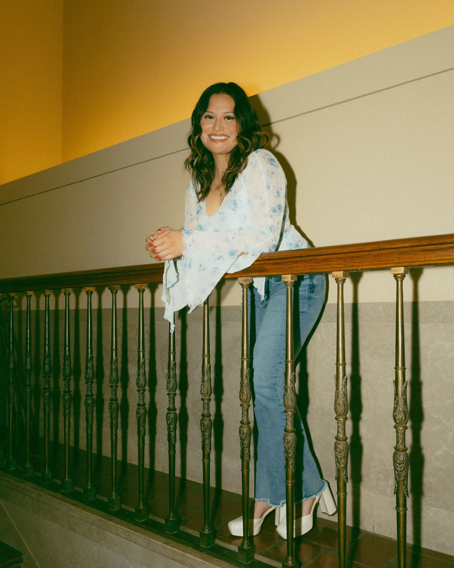 A sequence of photos showing a person in jeans and white top posing along a hallway railing with vintage lighting.