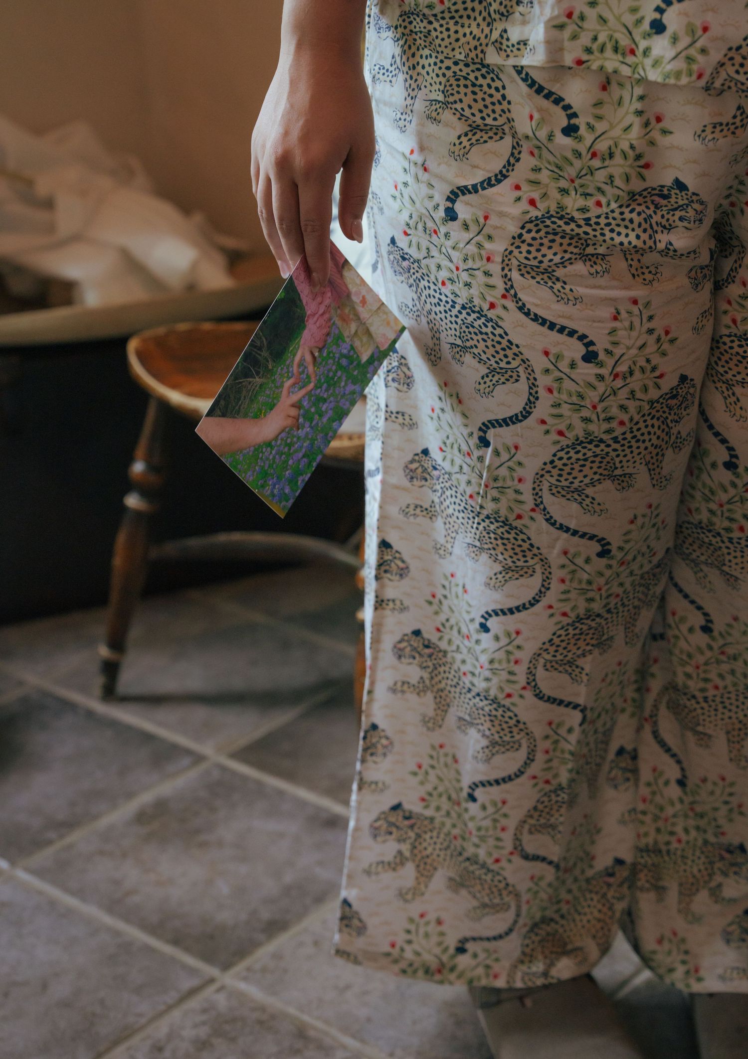 A person wearing patterned pajama pants stands on tile flooring in a dimly lit interior space.