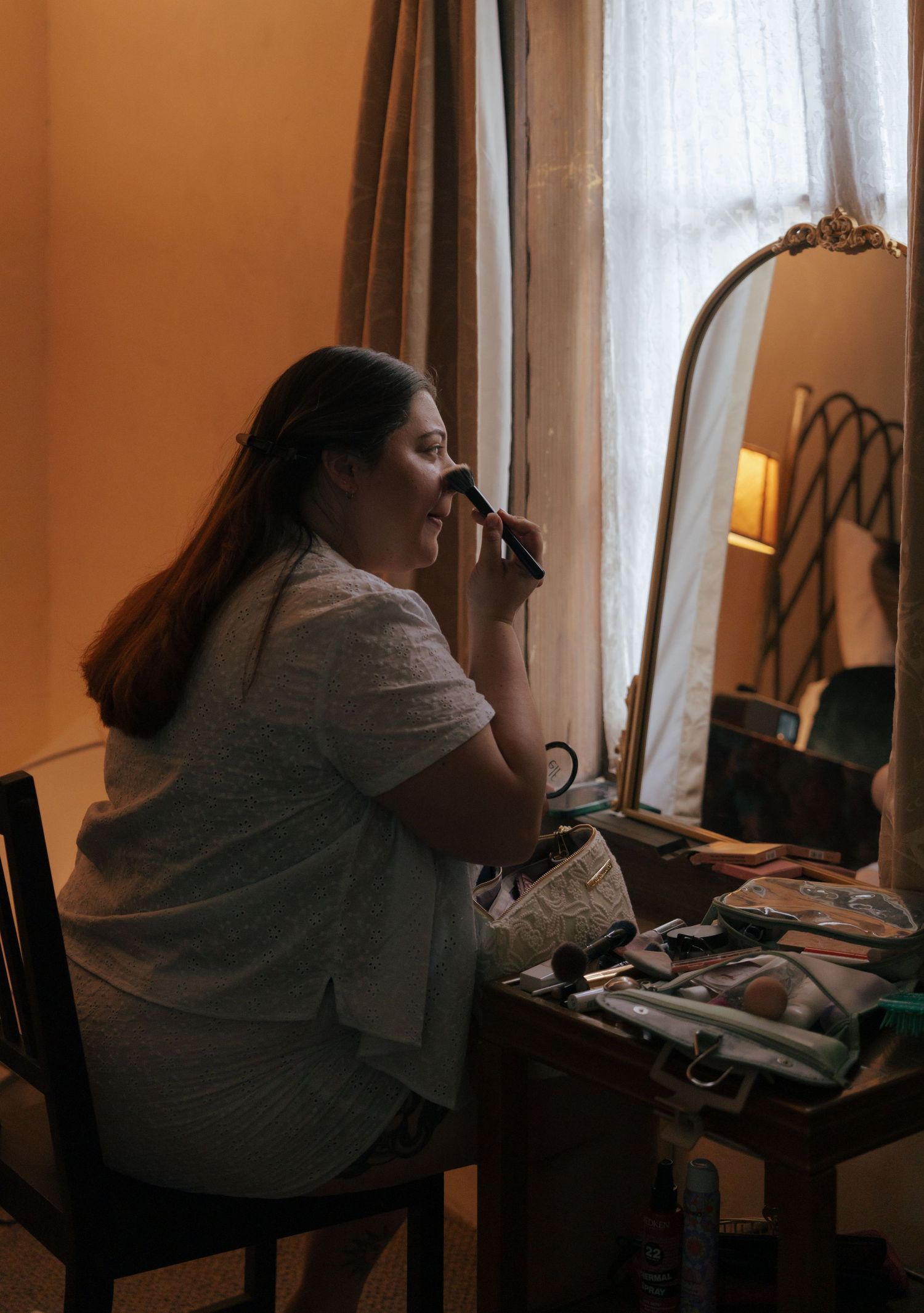 A person in a gray sweater sits at a desk near a window in a dimly lit room, creating a moody atmosphere.