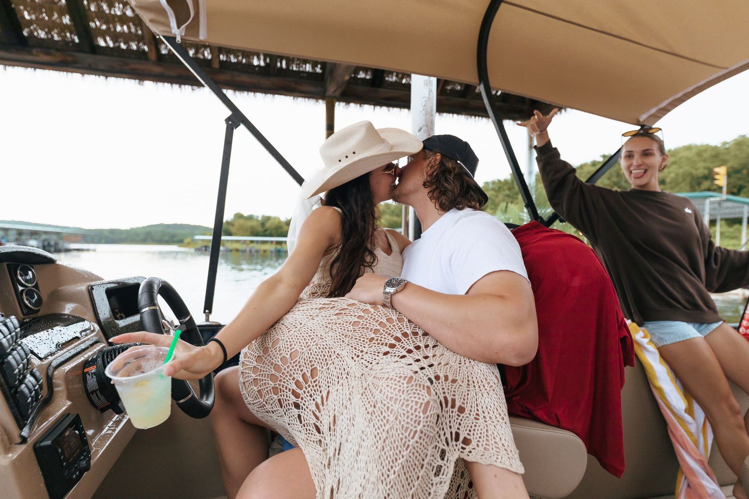 Friends enjoying drinks and conversation while relaxing on a pontoon boat during a summer day on the lake.