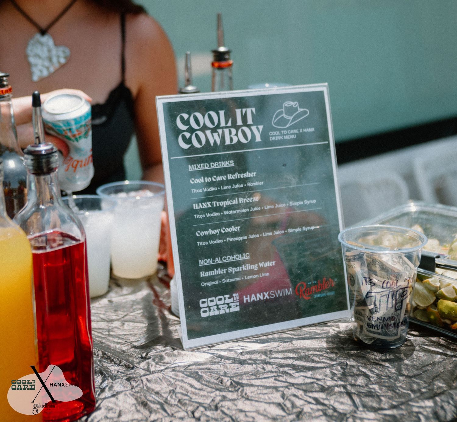 Drink menu signs and colorful beverages displayed on a patterned tablecloth.