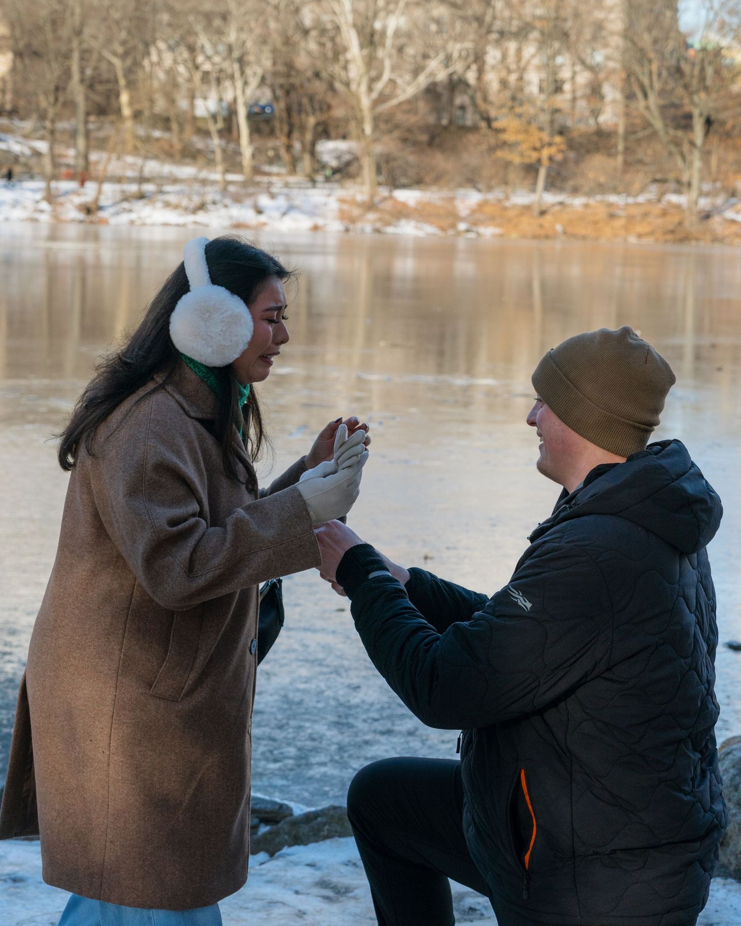 A couple shares a romantic moment by a frozen lake on a winter day.