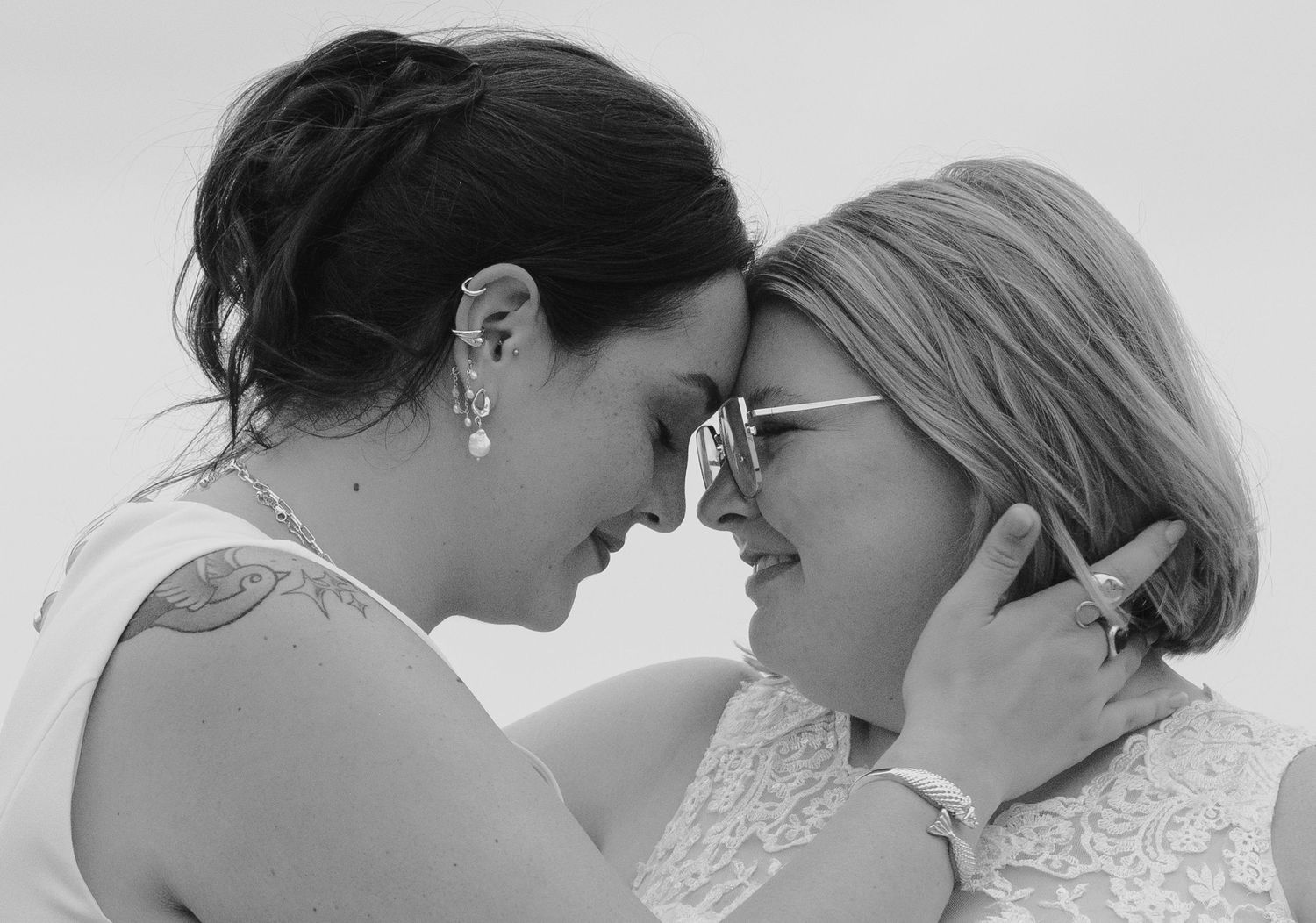 Black and white intimate portrait of two people in white lace sharing a tender moment together.