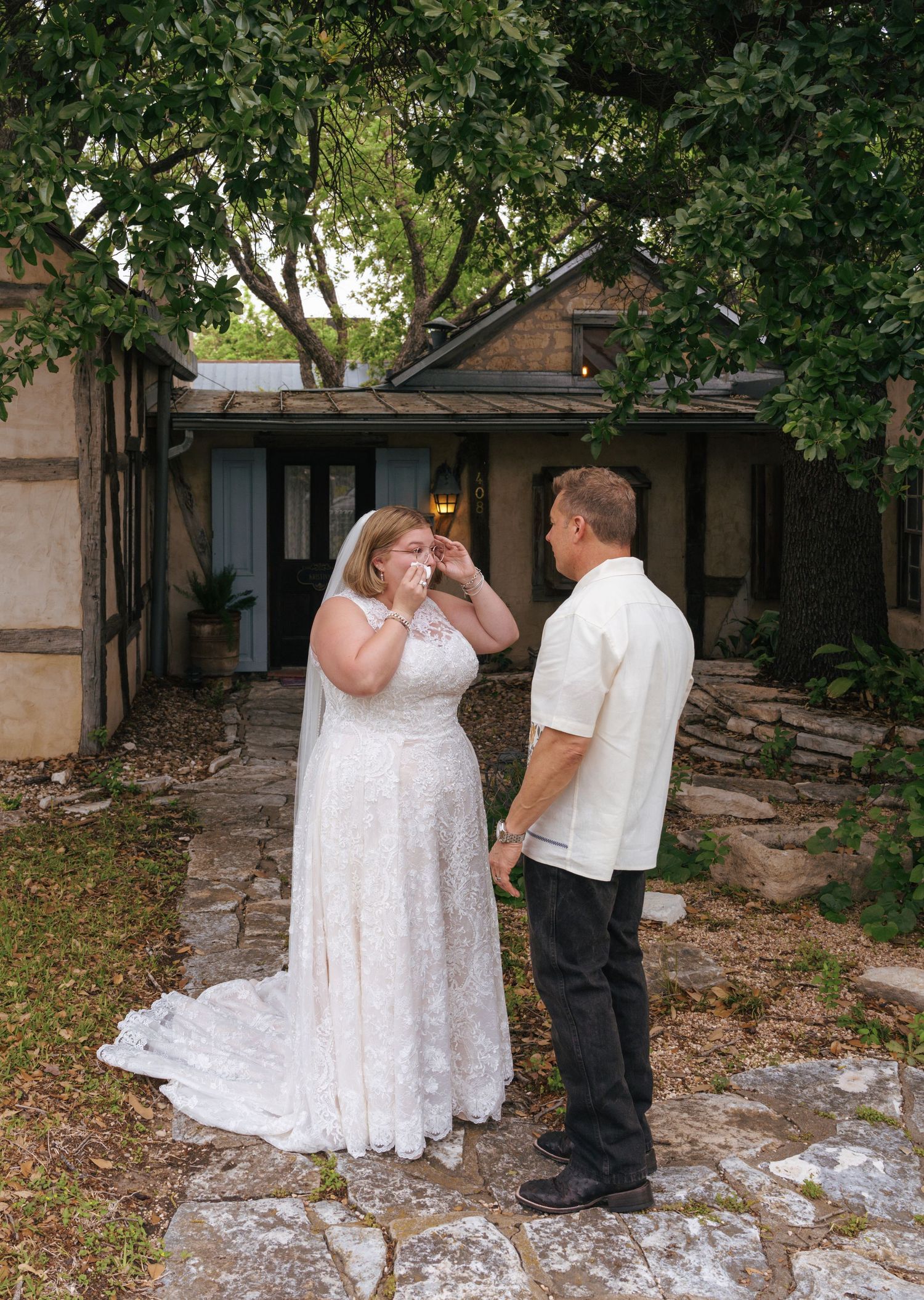 A couple in wedding attire shares an intimate first look moment in a garden courtyard setting.