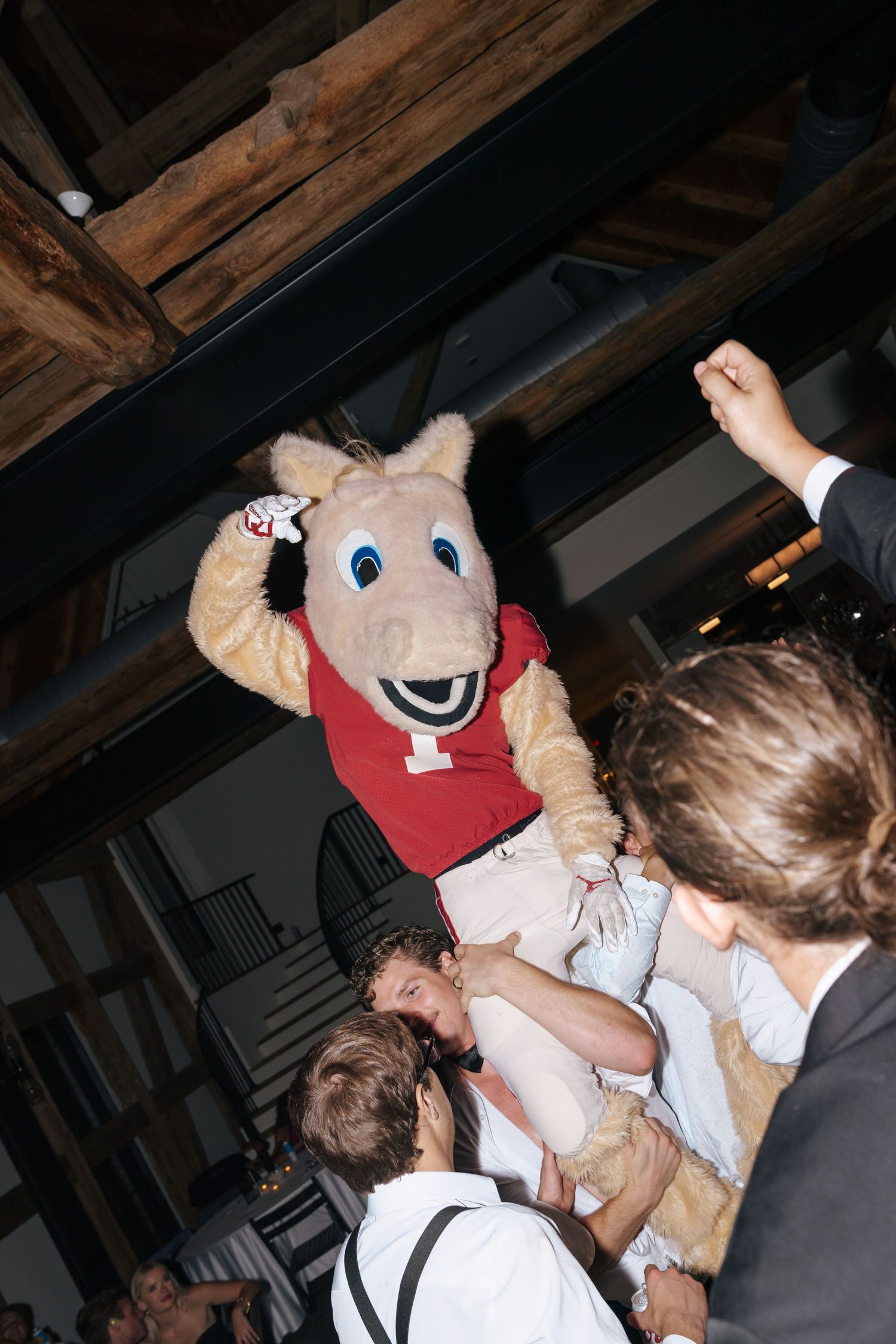 A mascot in a red cap entertaining party guests at an indoor venue.