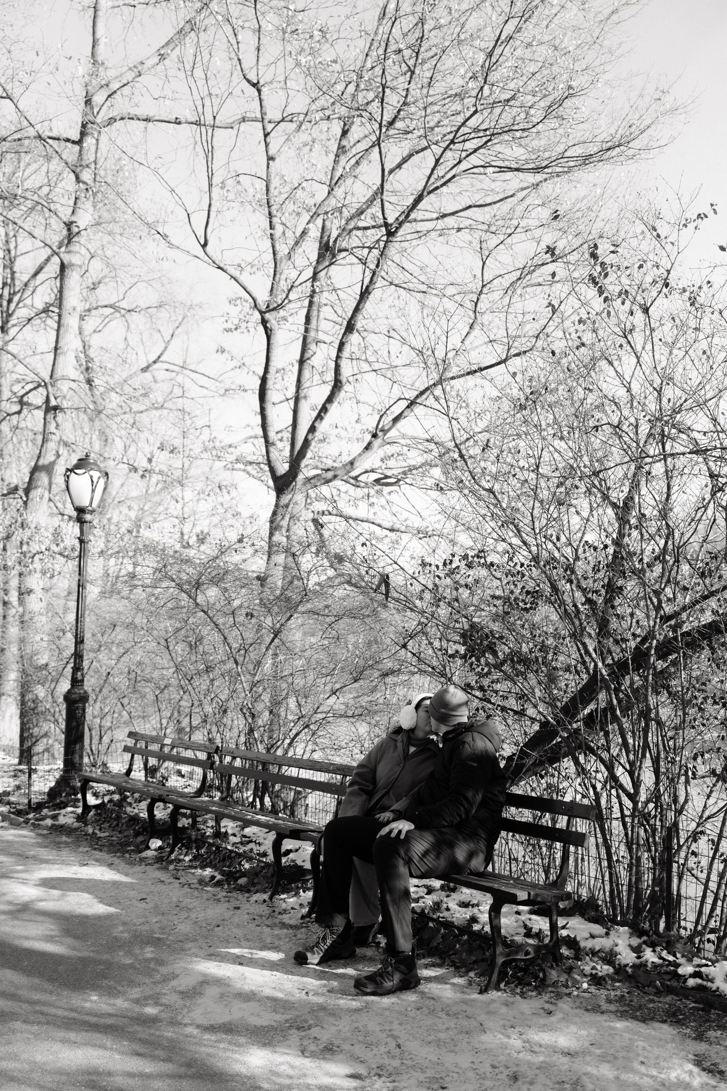 A sequence of vintage black and white photos showing someone resting on a park bench among bare winter trees.