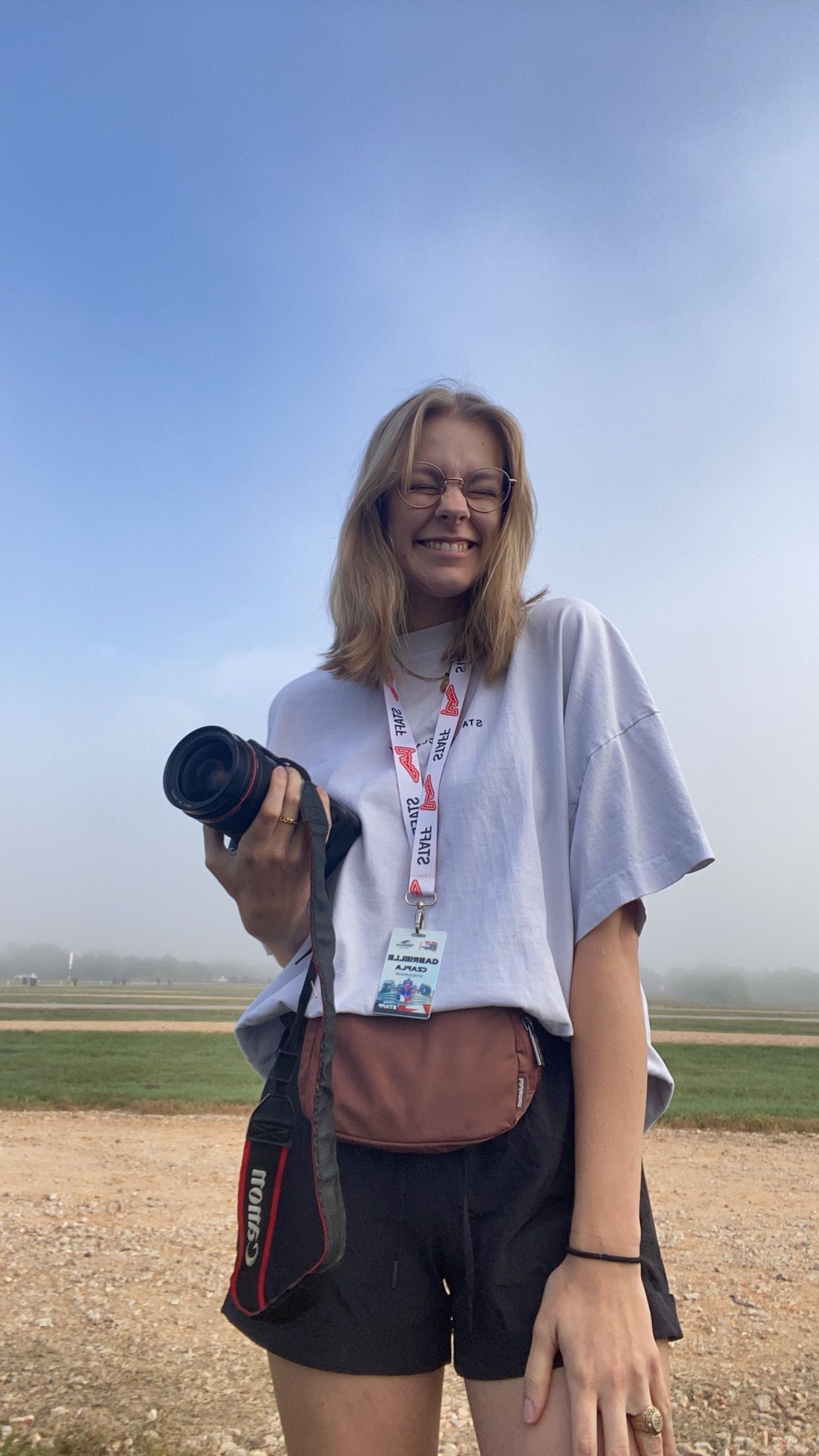 Person walking through a misty field carrying photography equipment.