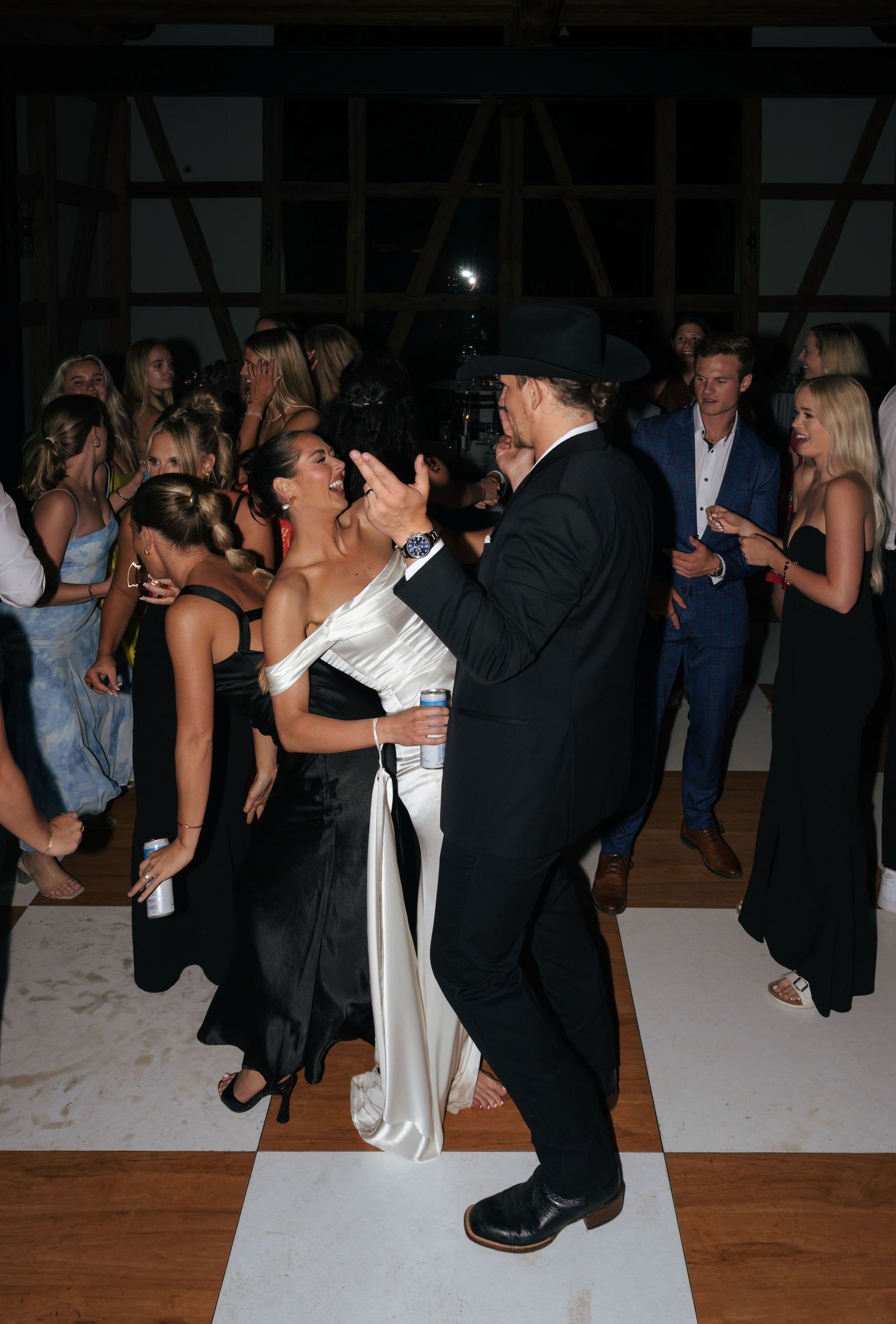 Wedding guests dance and celebrate on illuminated dance floor.