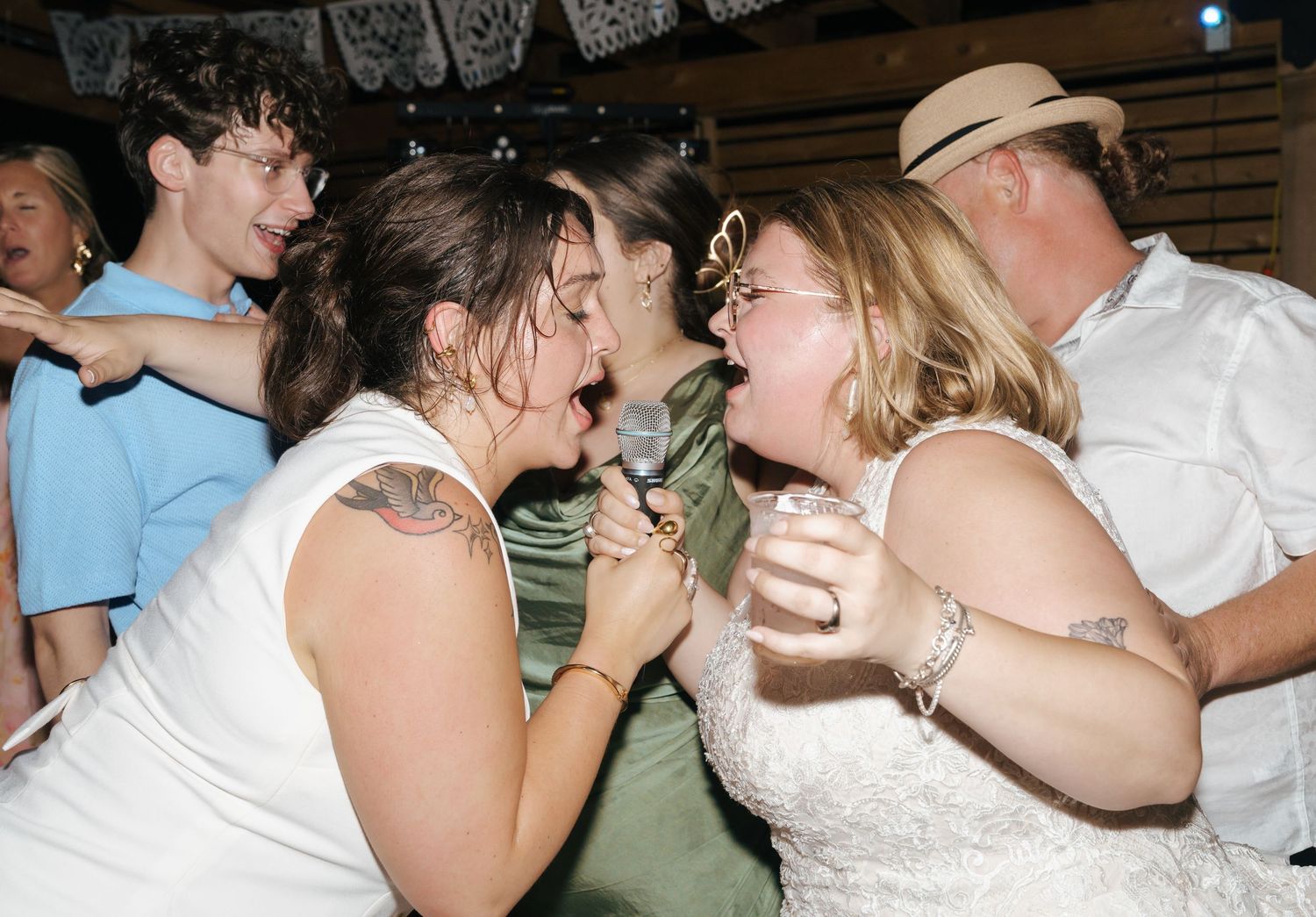 Couples dancing and embracing at a crowded party or social gathering.