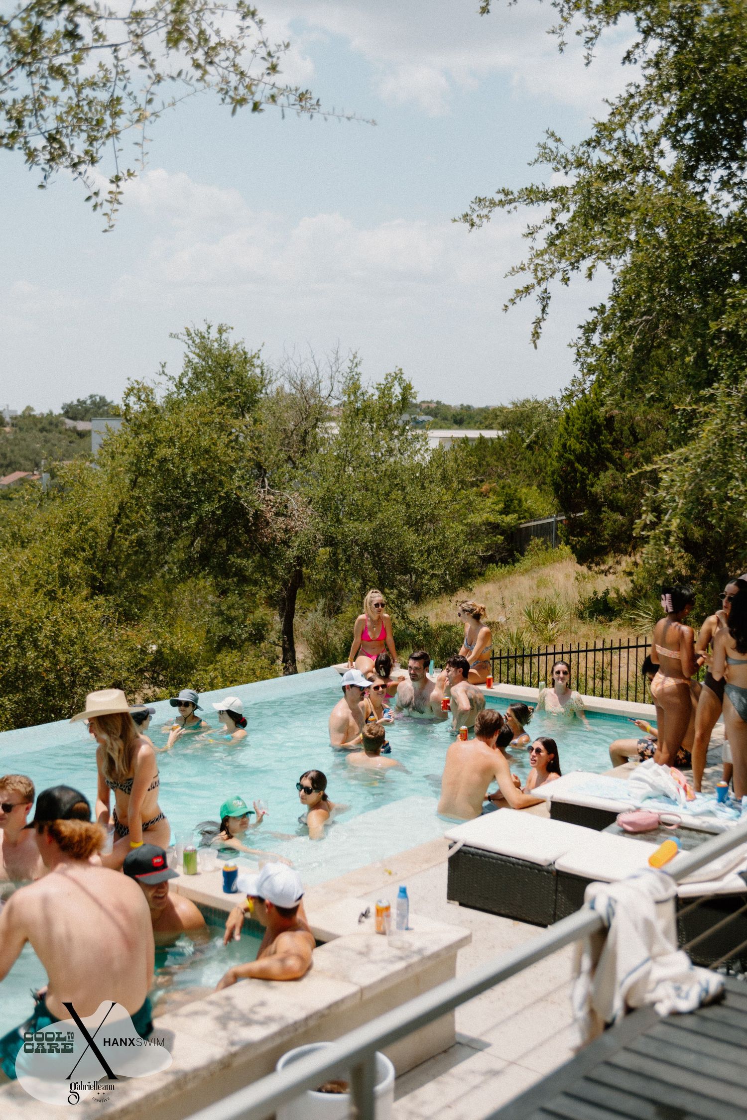 People enjoying a pool party at an outdoor venue with scenic hillside views.