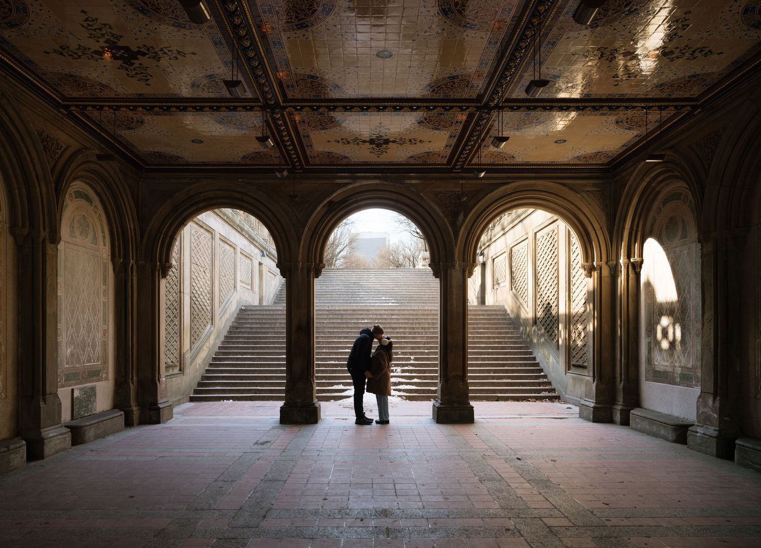 Dark archways and columns under Bethesda Terrace in Central Park with natural light filtering through.