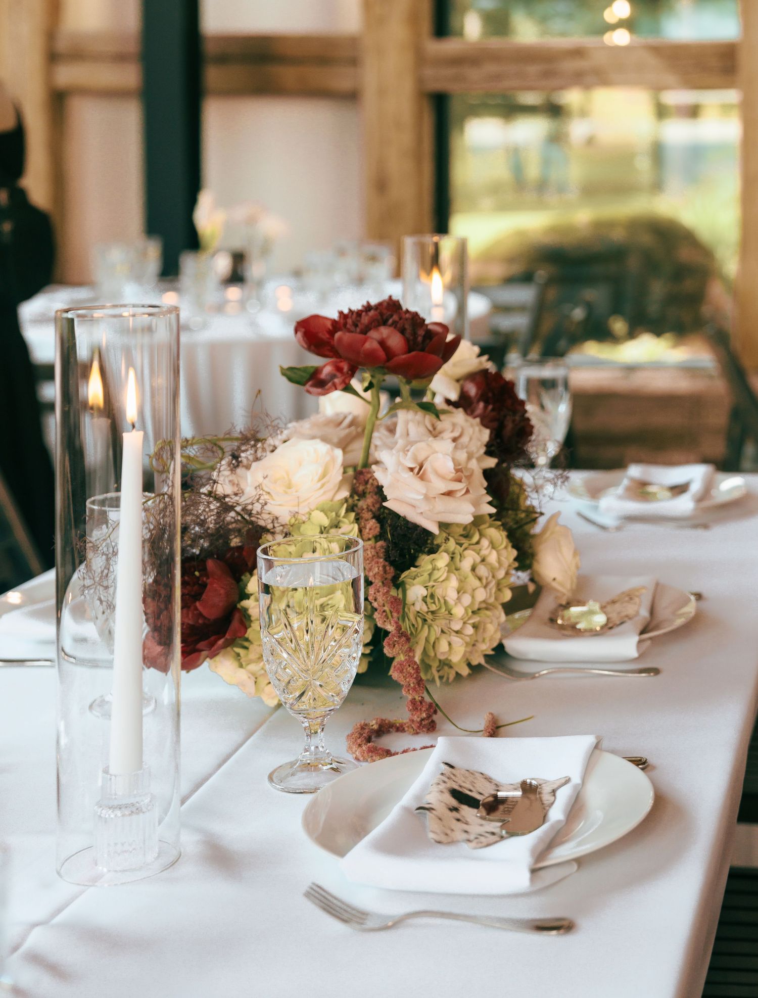 Elegant wedding reception table settings with floral centerpieces and crystal glassware on white tablecloths.