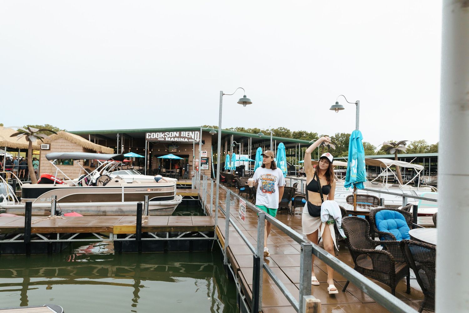 Scenic view of a marina boardwalk with boats docked along wooden piers and waterfront buildings on a sunny day.