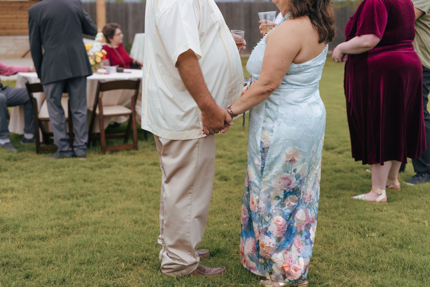 Guests dancing together at an outdoor wedding reception on a grassy lawn.