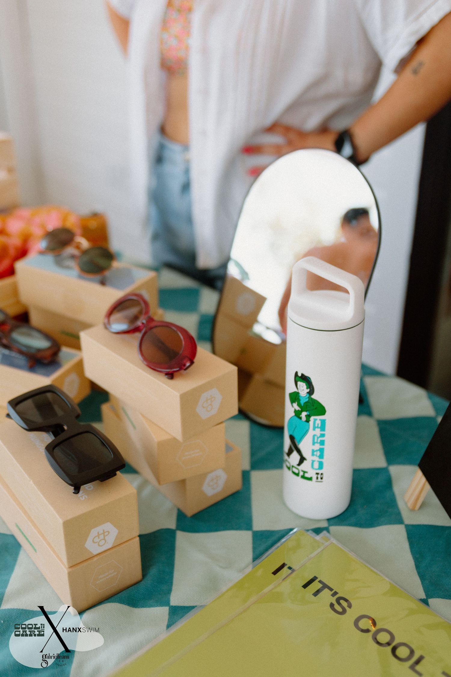 Product flatlay featuring white bottles and branded packaging on turquoise surface.