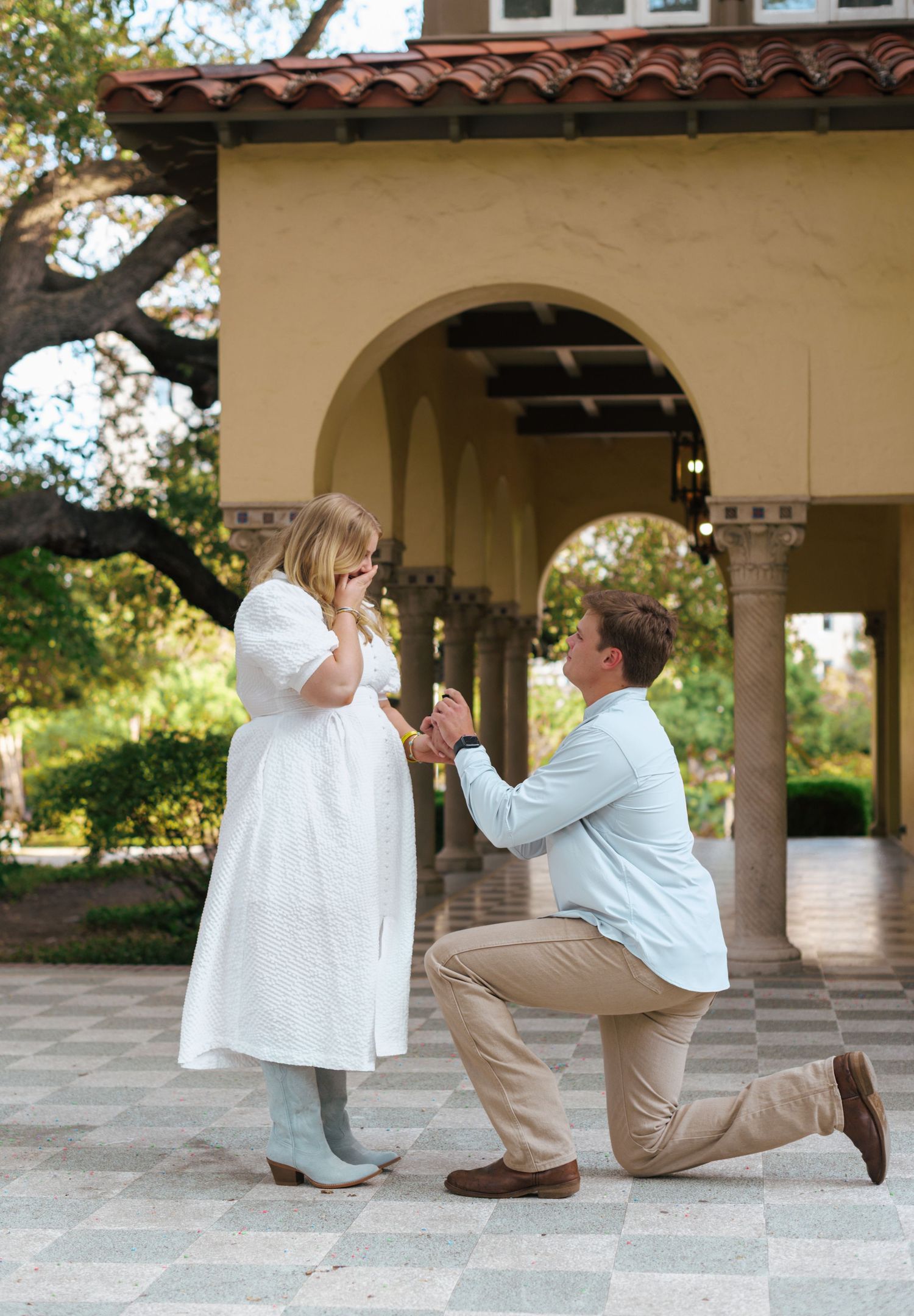 A romantic marriage proposal sequence unfolds under a Mediterranean-style archway in a garden setting.