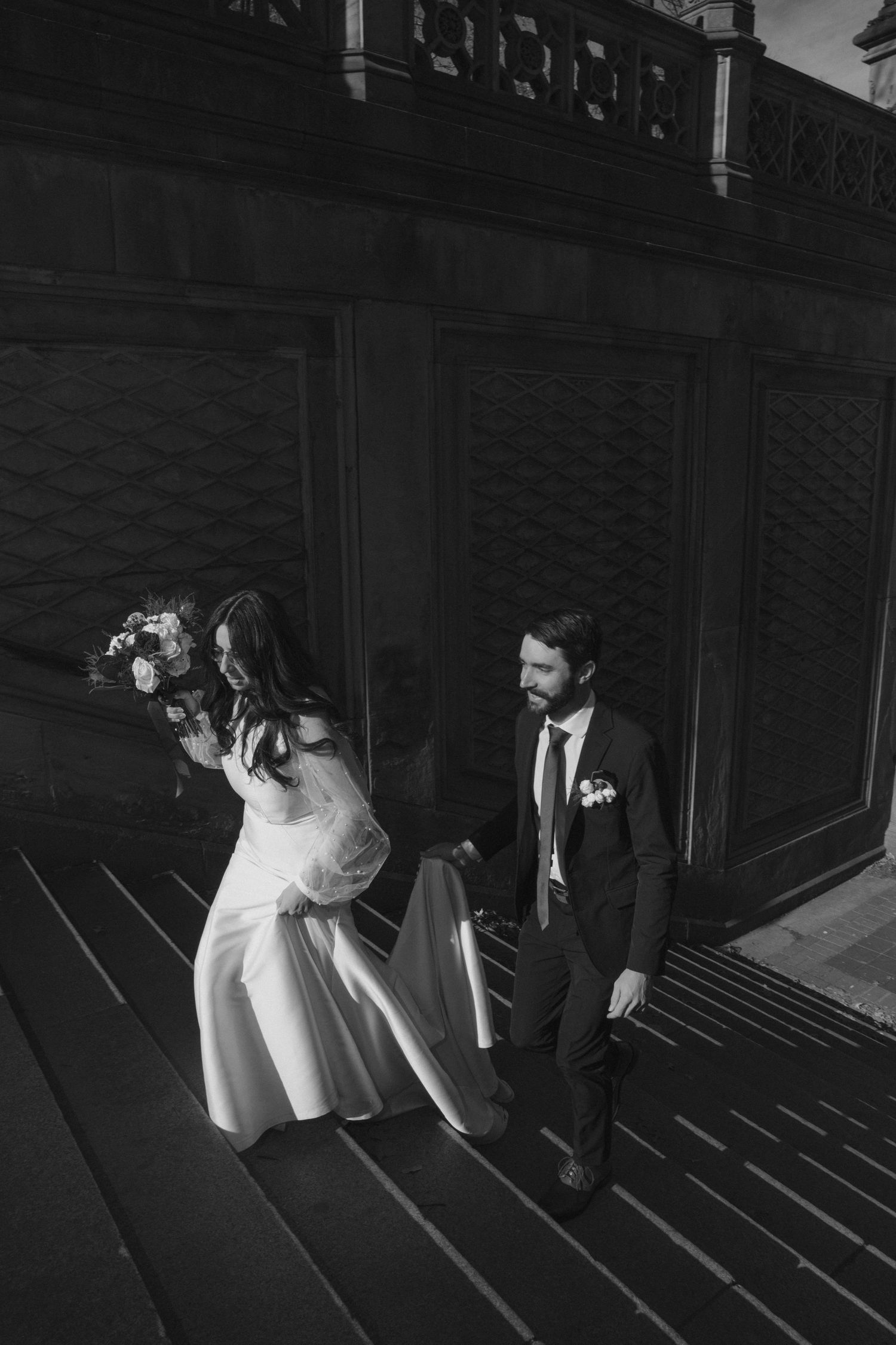 Dramatic black and white wedding photo showing shadows cast on steps with bride and groom.