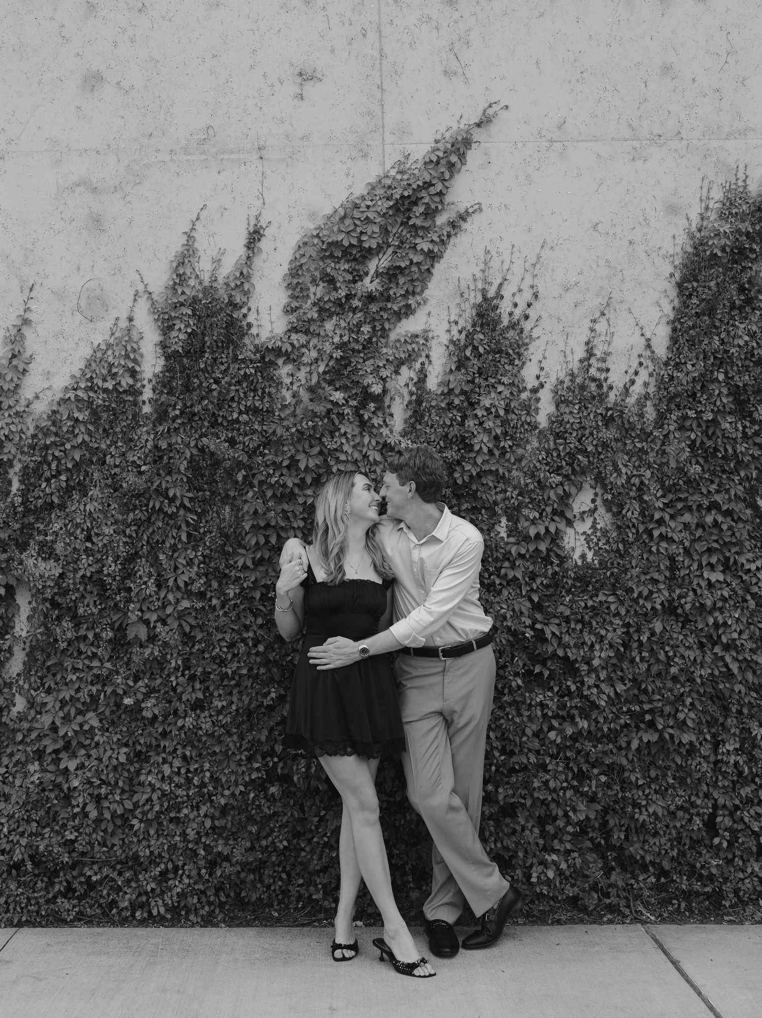 A couple dancing in a romantic sequence against a hedge wall, showing graceful dips and embraces in black and white.