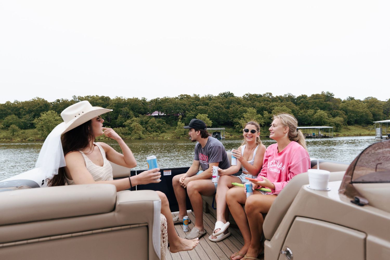 Friends enjoying drinks and conversation while relaxing on a pontoon boat during a summer afternoon.