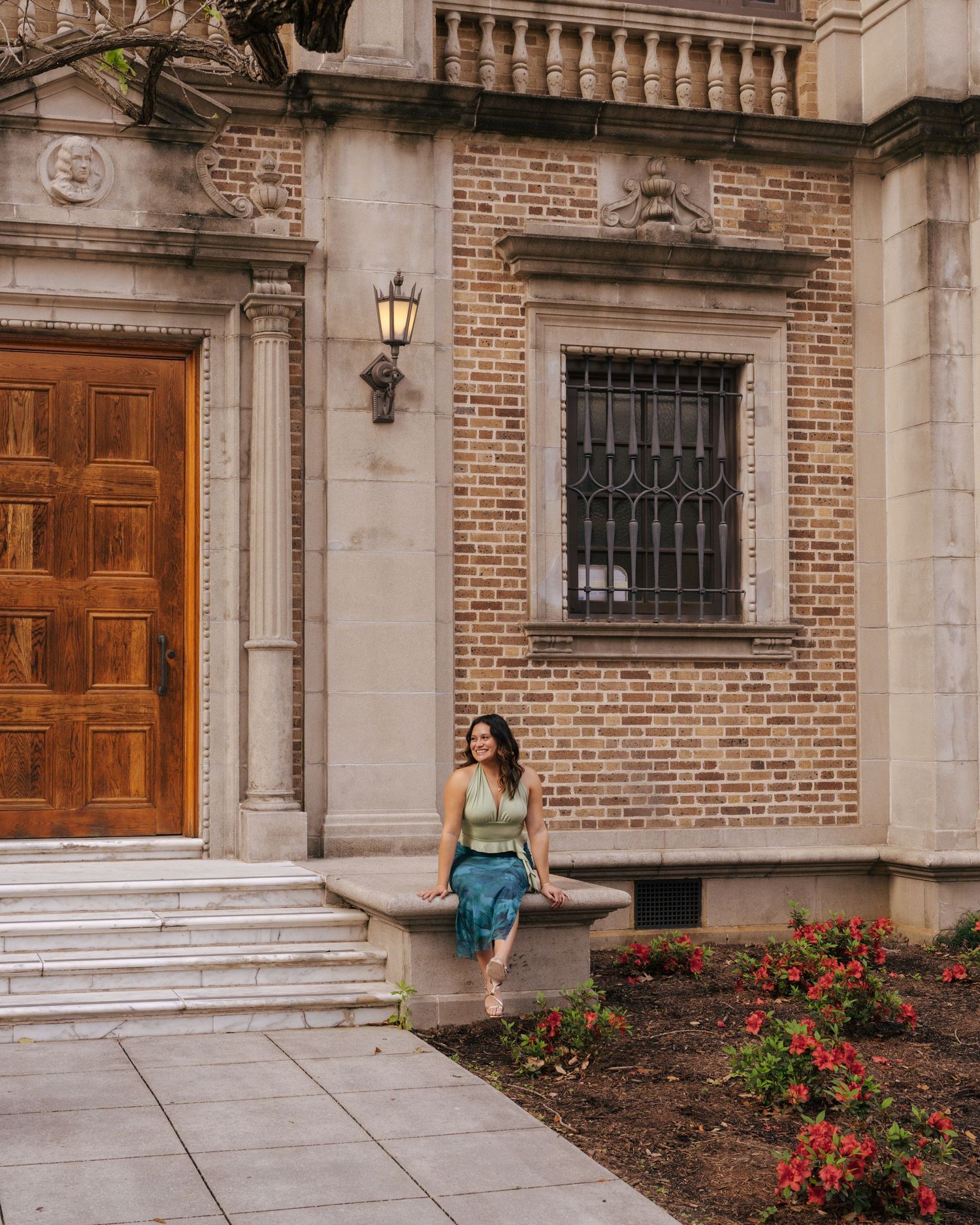 Person stands in front of a grand brick building entrance with wooden doors and ornate architectural details.