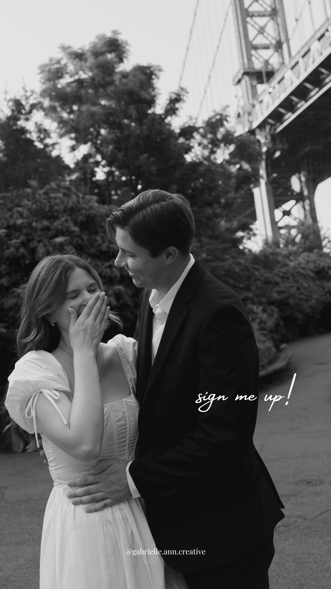 A couple in formal attire share a romantic moment outdoors near a bridge structure in black and white.