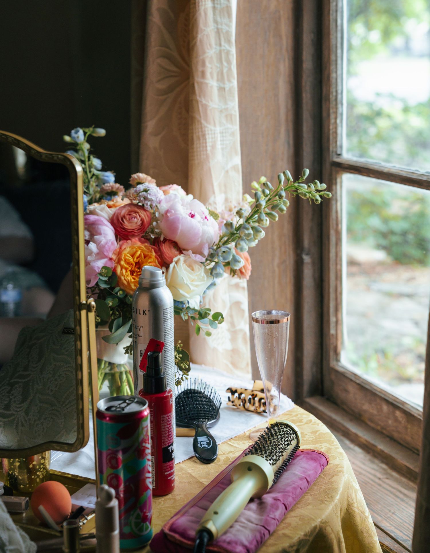 Colorful floral arrangements in glass vases line a rustic windowsill with soft natural lighting filtering through.