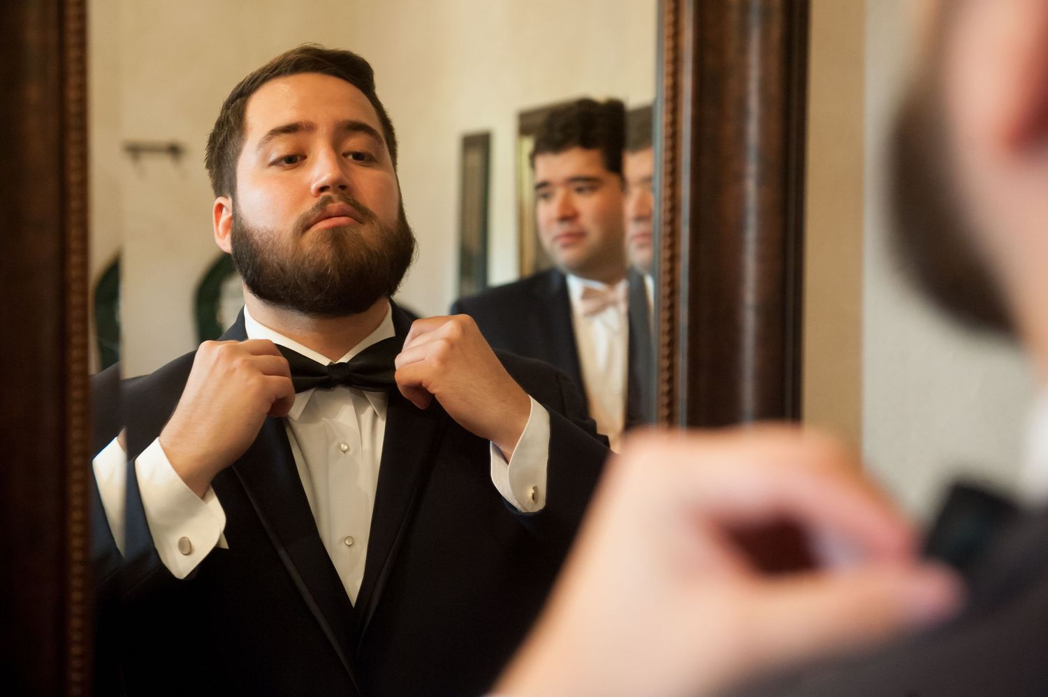 Groom getting ready sequence in formal attire with vintage mirror backdrop.