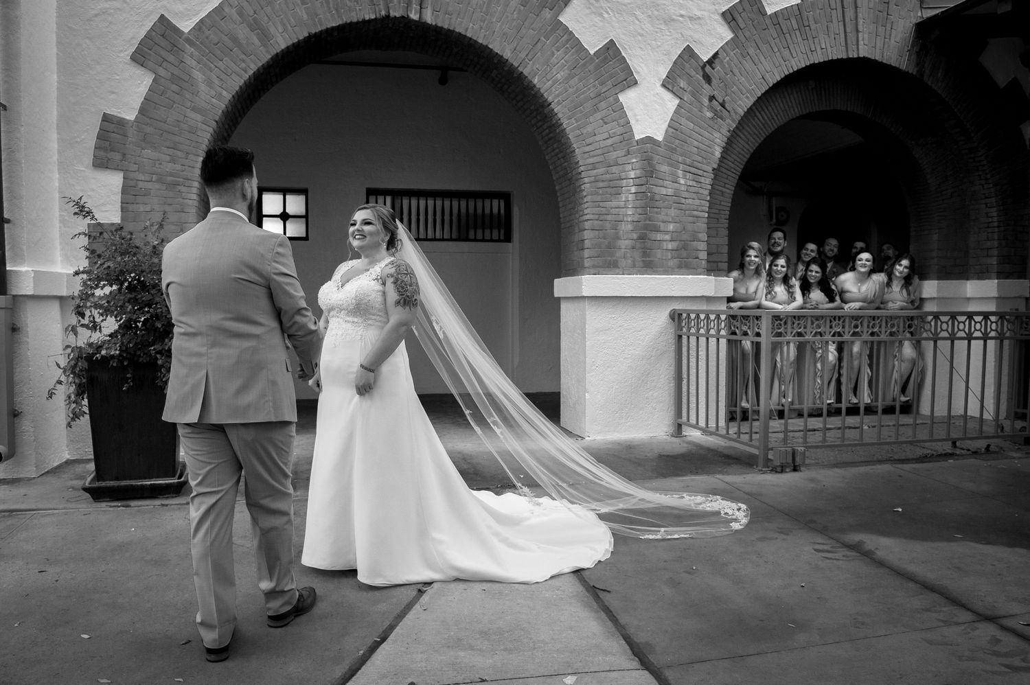 A wedding ceremony moment captured in black and white under brick archways.