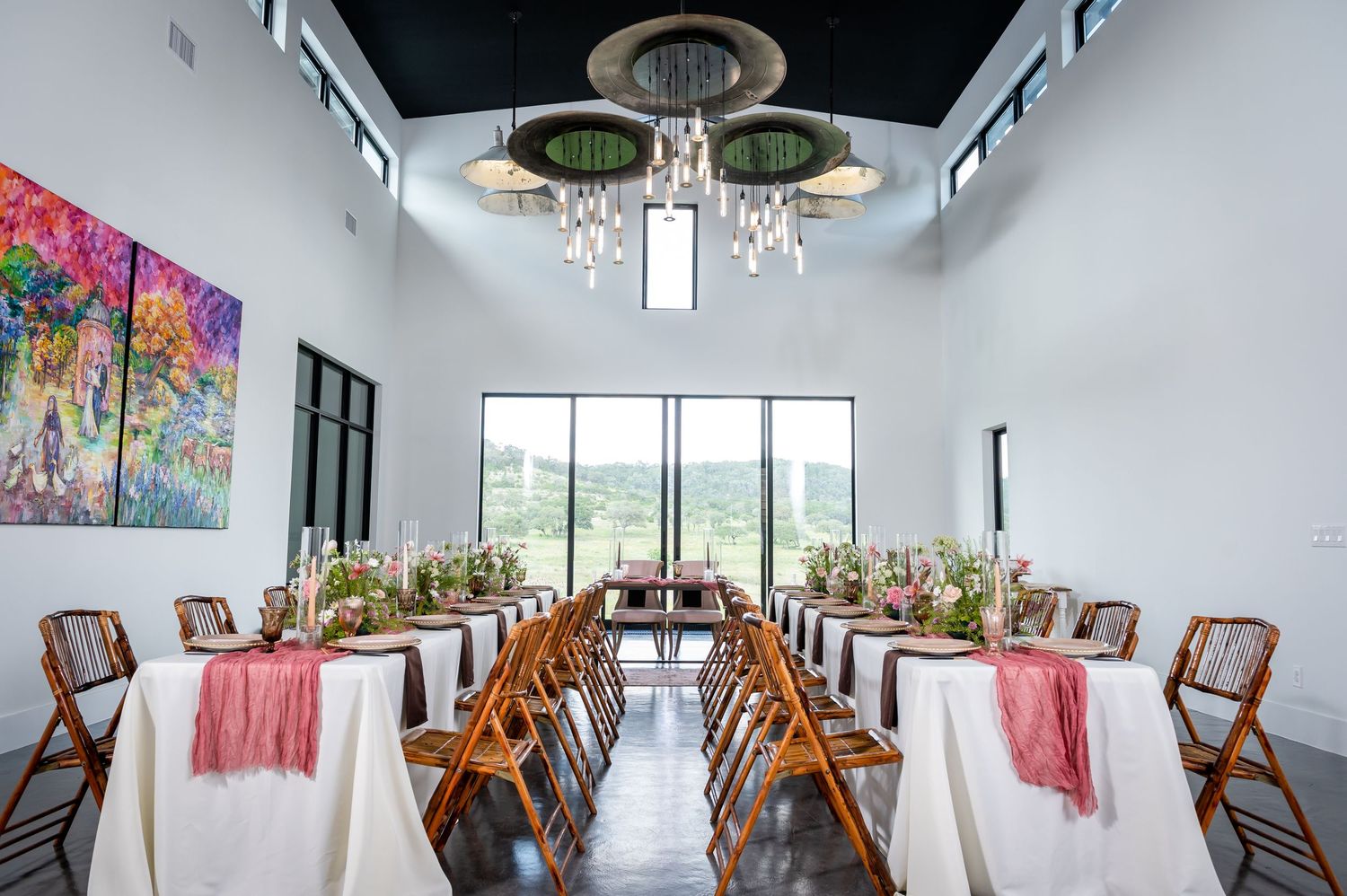 Modern white event space with wooden chairs and colorful wall art features.