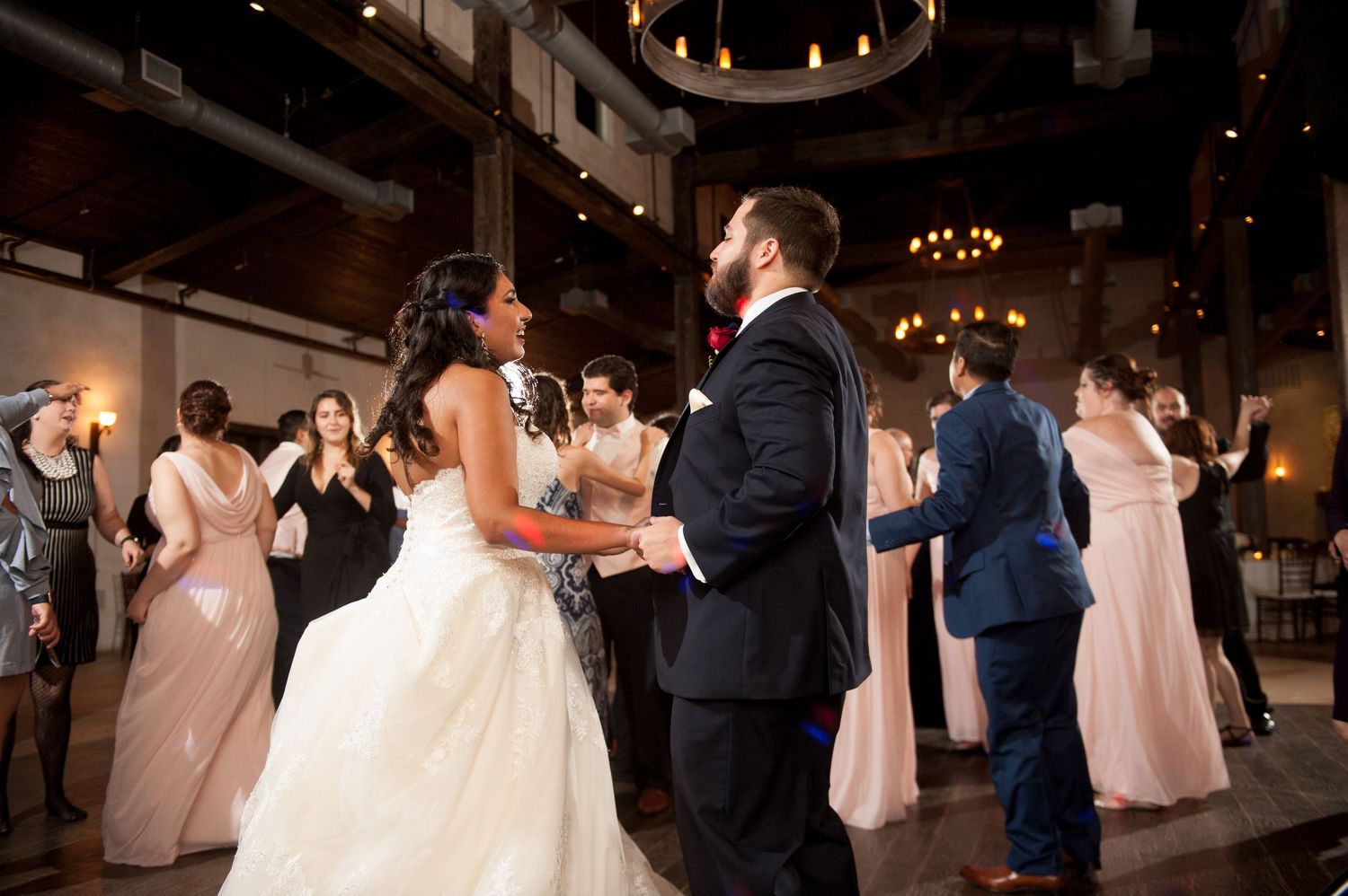 Couples dance together during a romantic wedding reception under warm lighting.