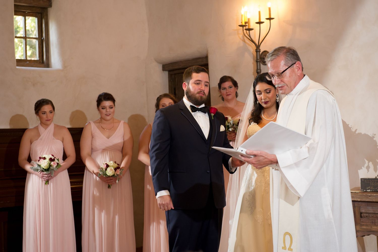 Wedding ceremony participants stand in formation inside a traditional church setting.
