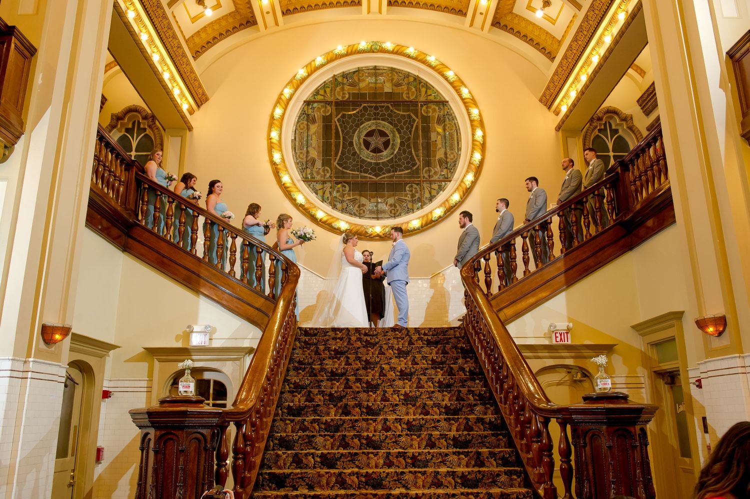 A panoramic view of a historic venue's grand staircase with ornate architectural details and golden accents.