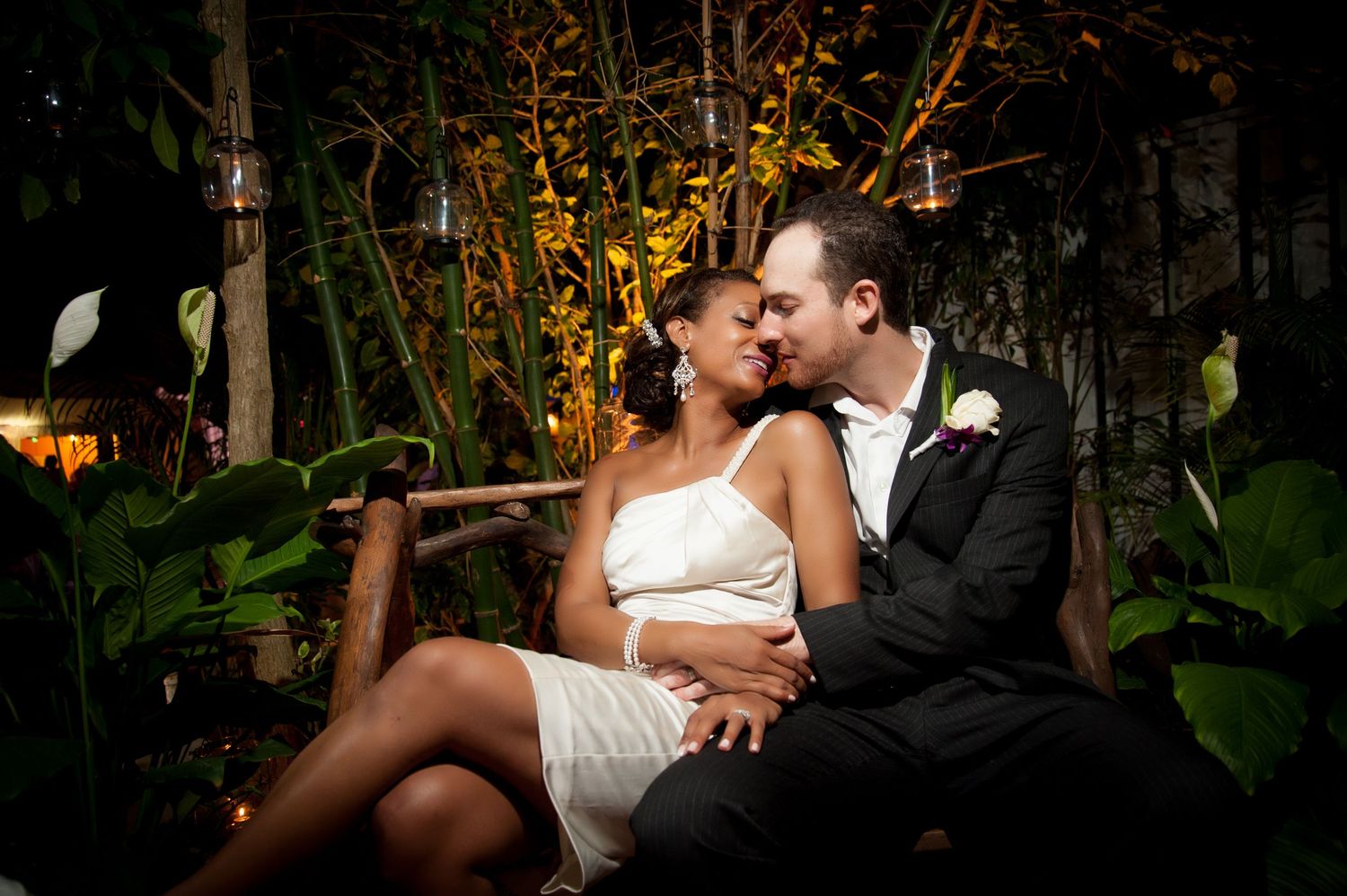 Intimate evening portrait of couple among tropical garden foliage.