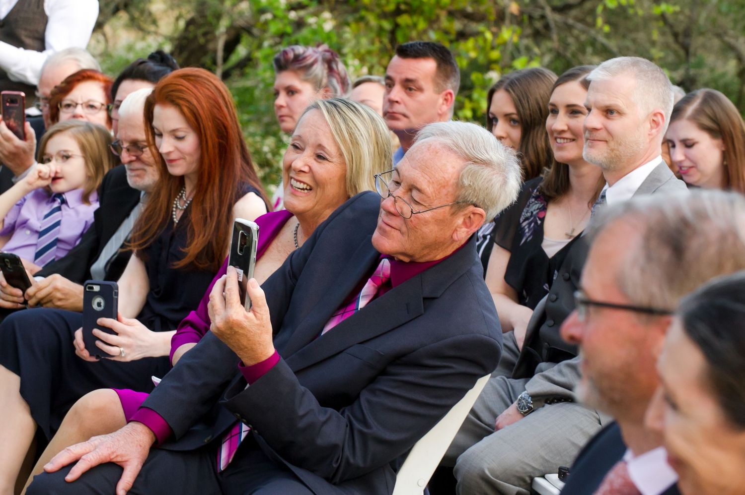 Wedding ceremony guests seated outdoors watching emotional moment unfold.