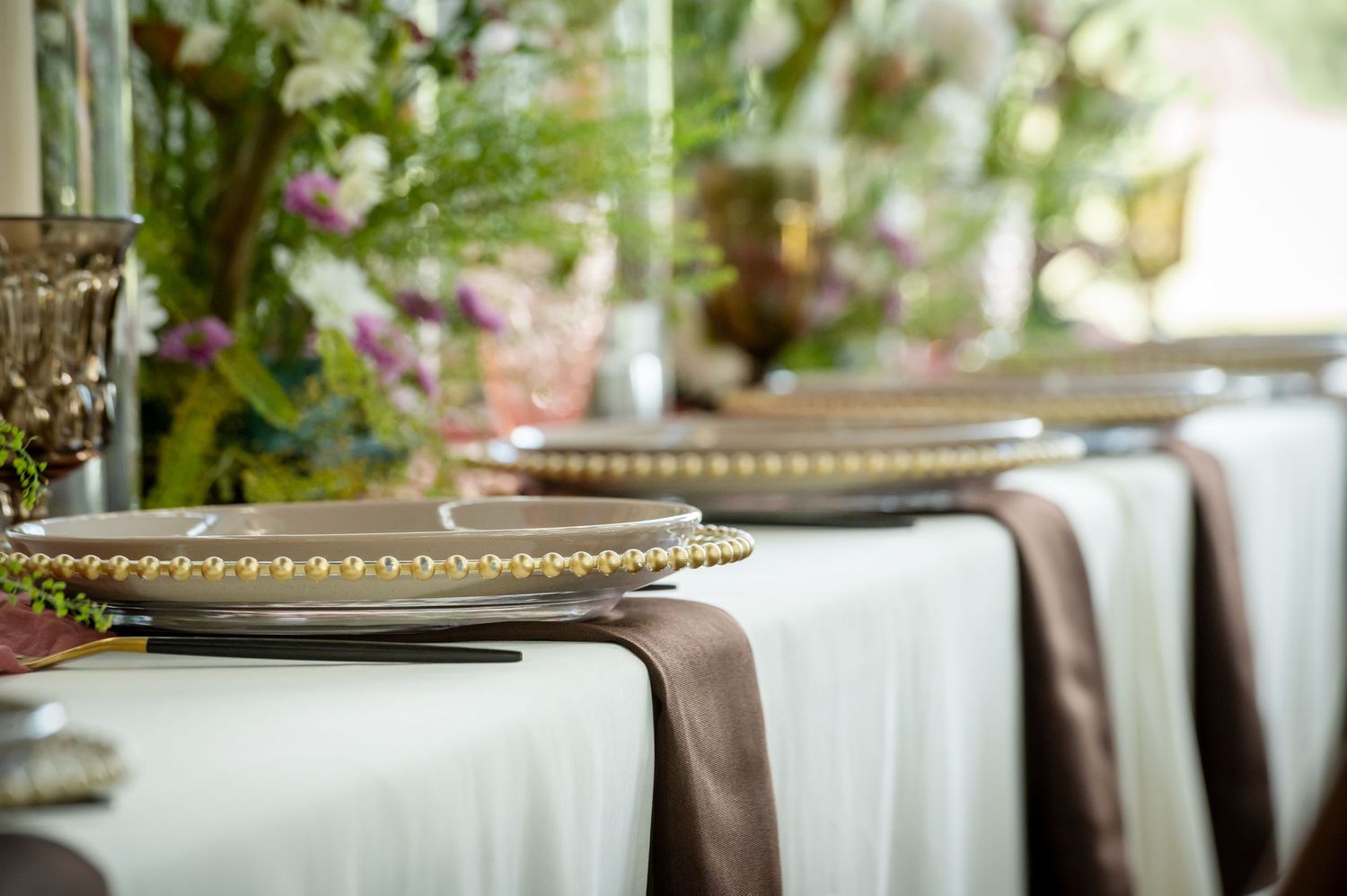 Elegant wedding reception table settings with floral centerpieces and crystal details.