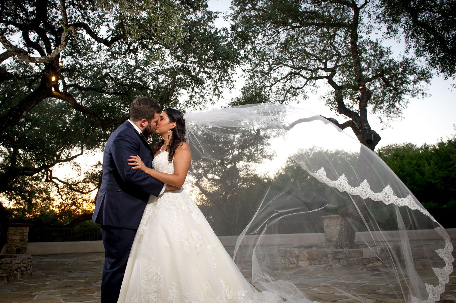 Dramatic wedding photos with flowing veil against natural outdoor backdrop.