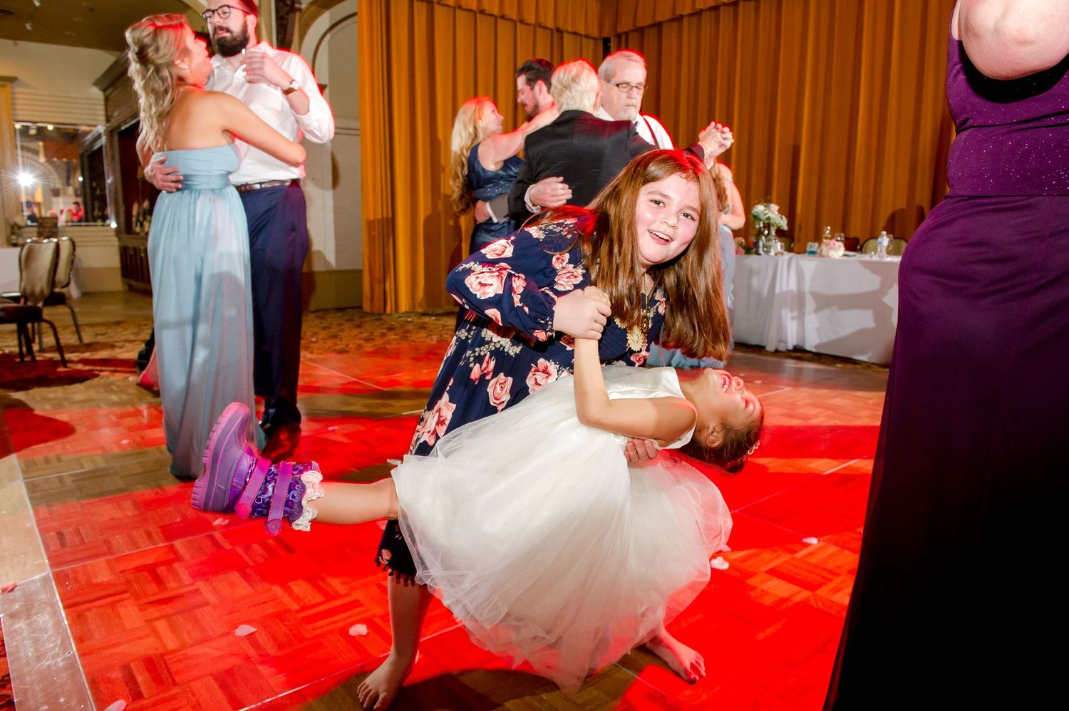 Wedding reception dance floor with guests enjoying upbeat celebration on red carpet.