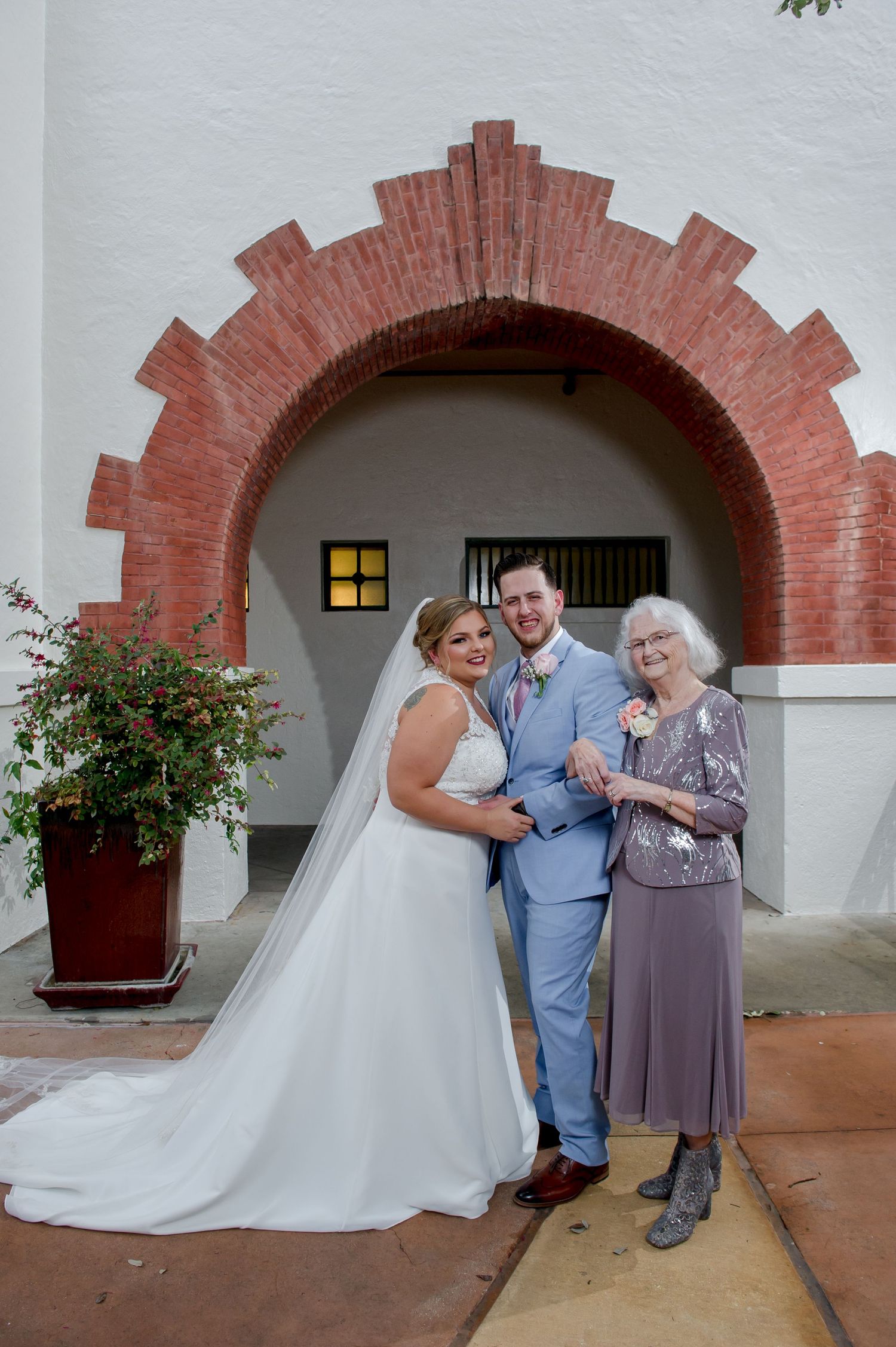 Wedding party poses under decorative brick archways with white walls and terra cotta accents.