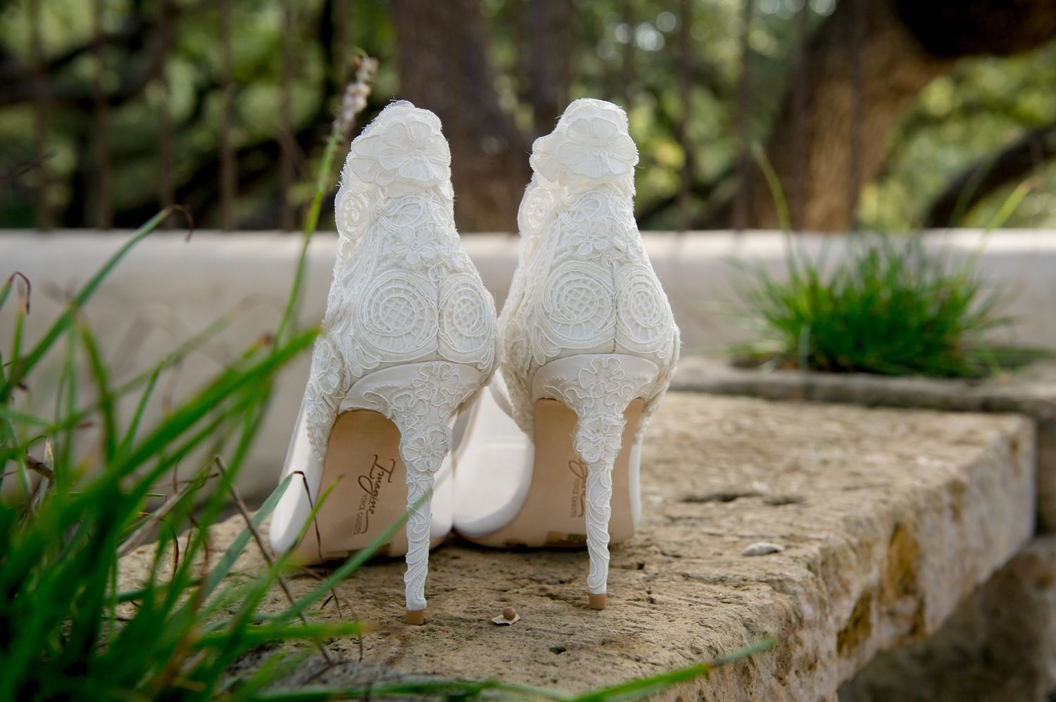 White bridal heels displayed on rustic stone surface.