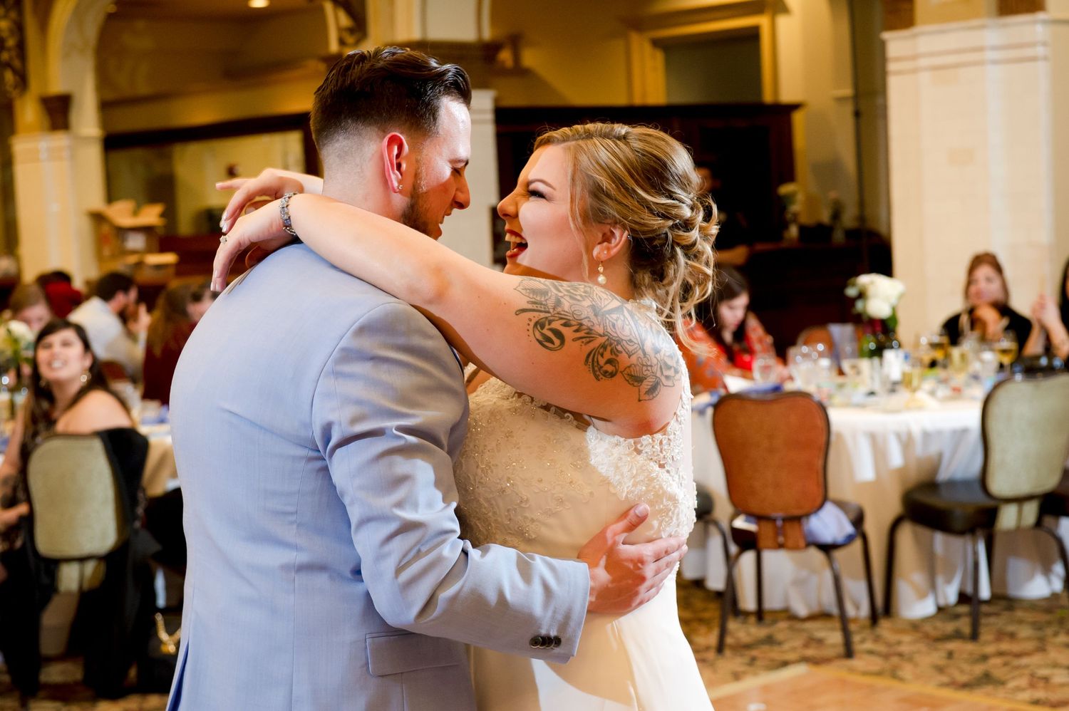 Wedding couple shares a romantic dance surrounded by guests at an elegant reception venue.