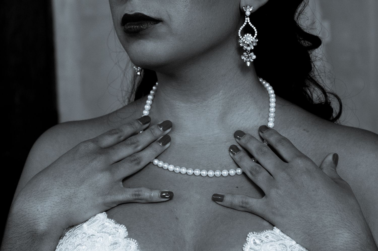 Artistic black and white detail of pearl necklace and dangling earrings with strapless gown.