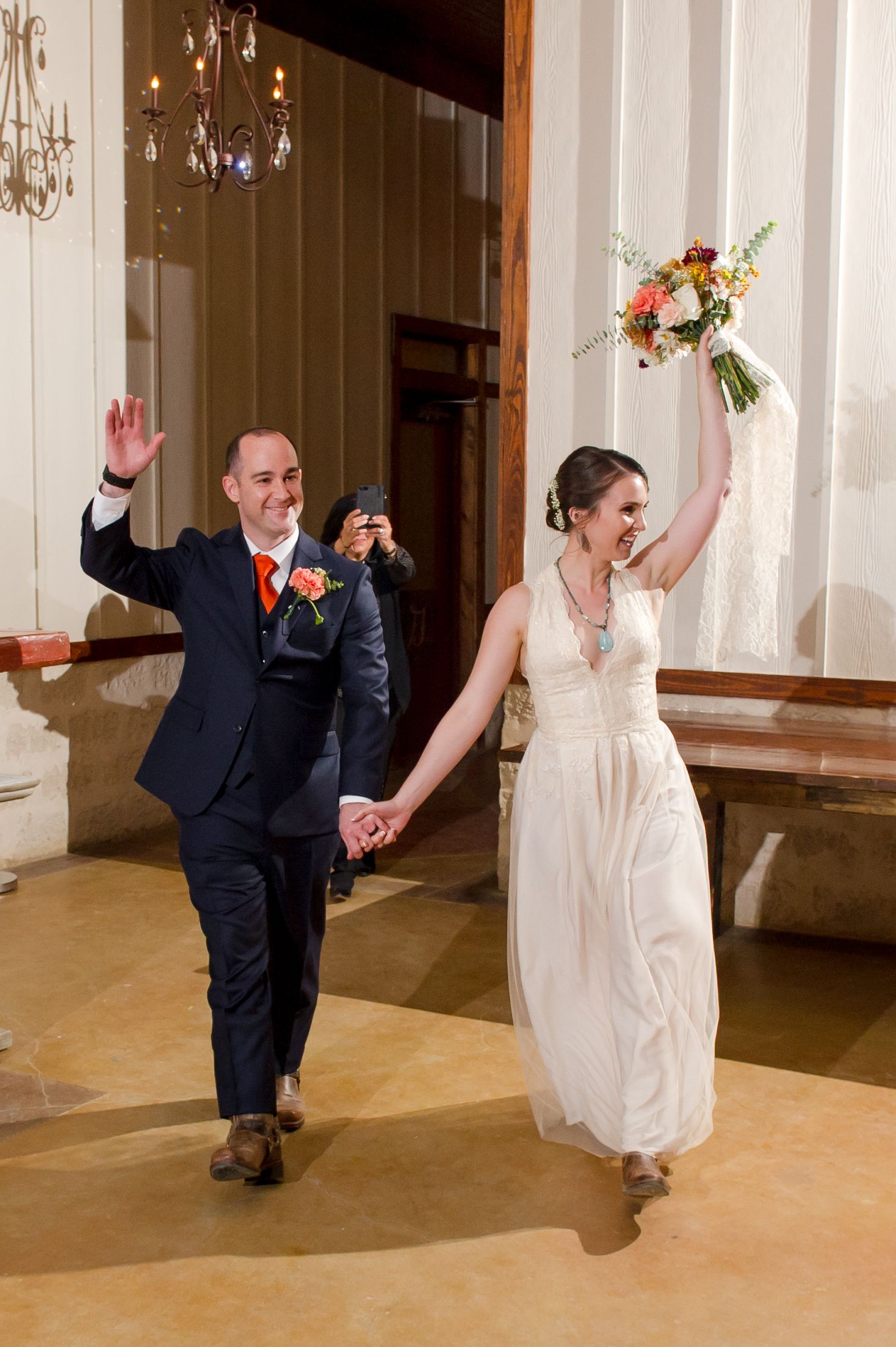 Wedding party members strike fun poses in an elegant indoor venue with white columns.