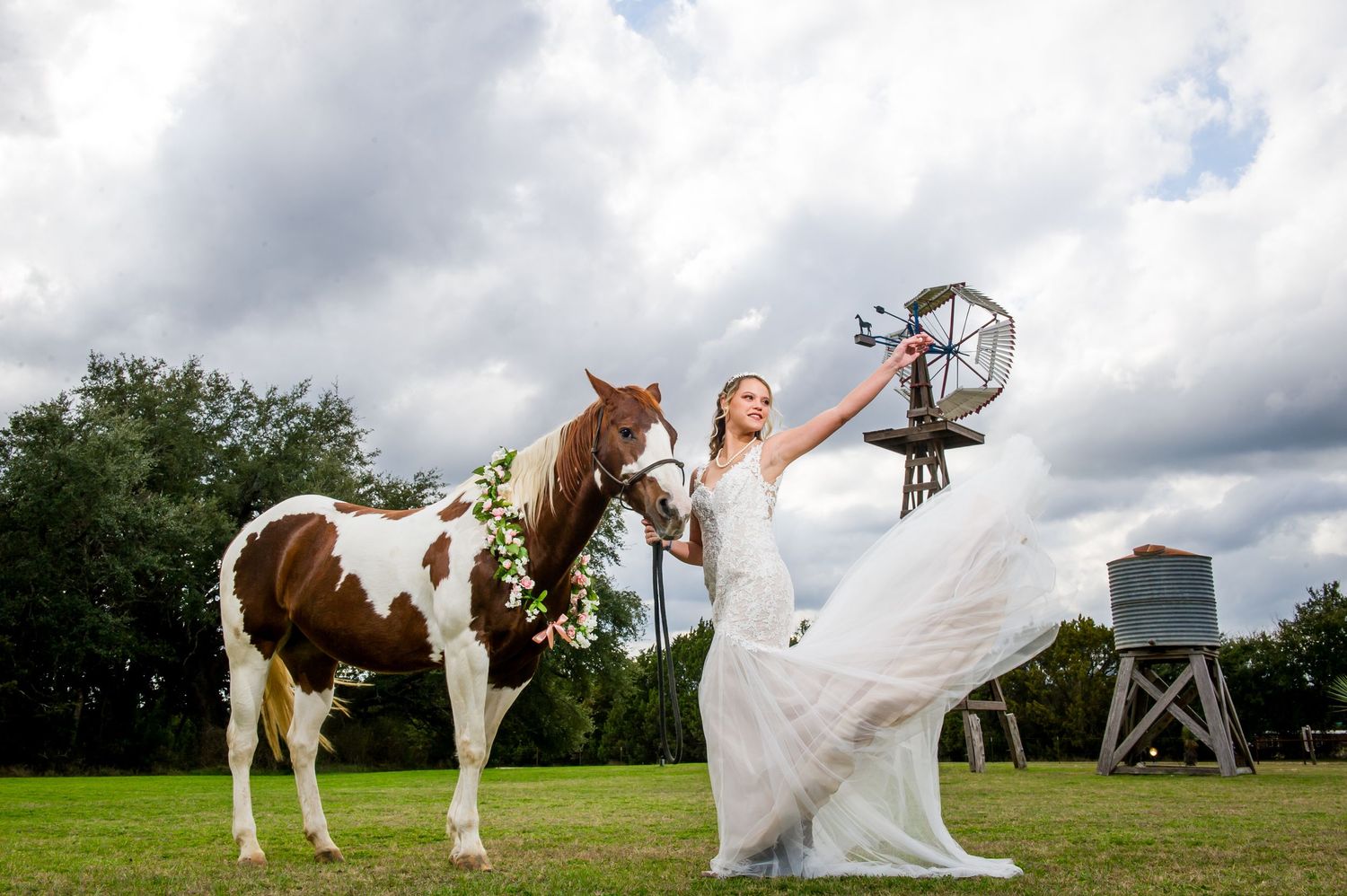 Wedding dress photo with paint horses in a green pasture under cloudy skies.