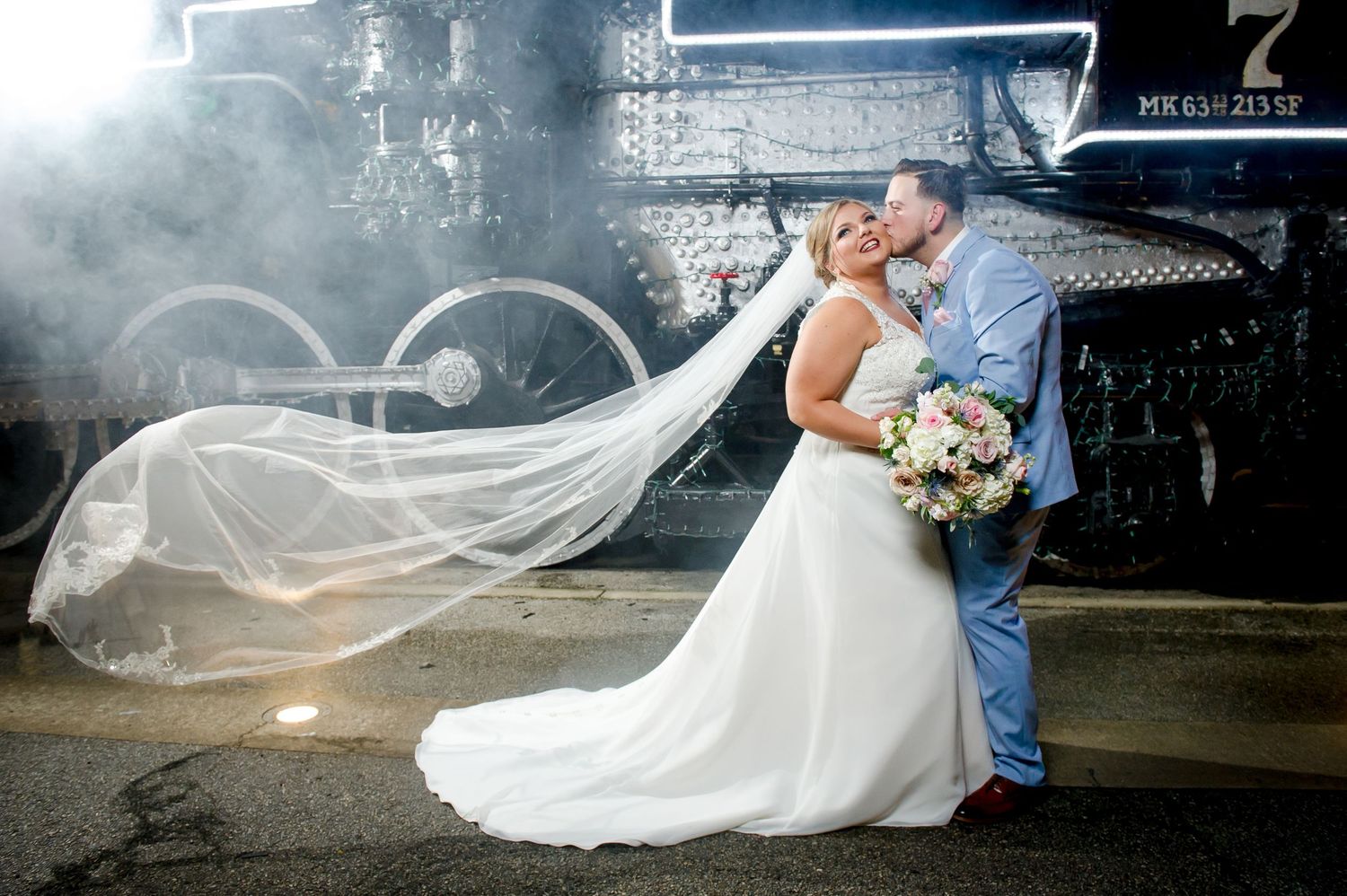 Dramatic wedding portraits with flowing veil against vintage railway setting.