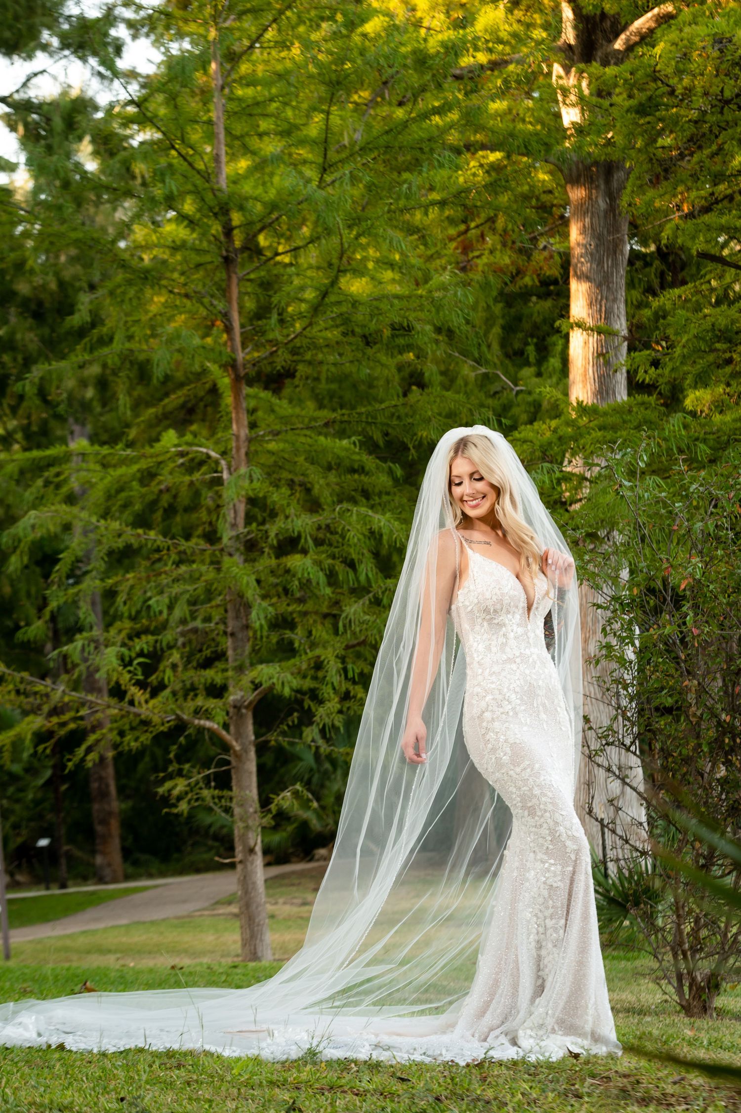 Elegant bridal portraits in a park setting with flowing cathedral veil and fitted lace gown.